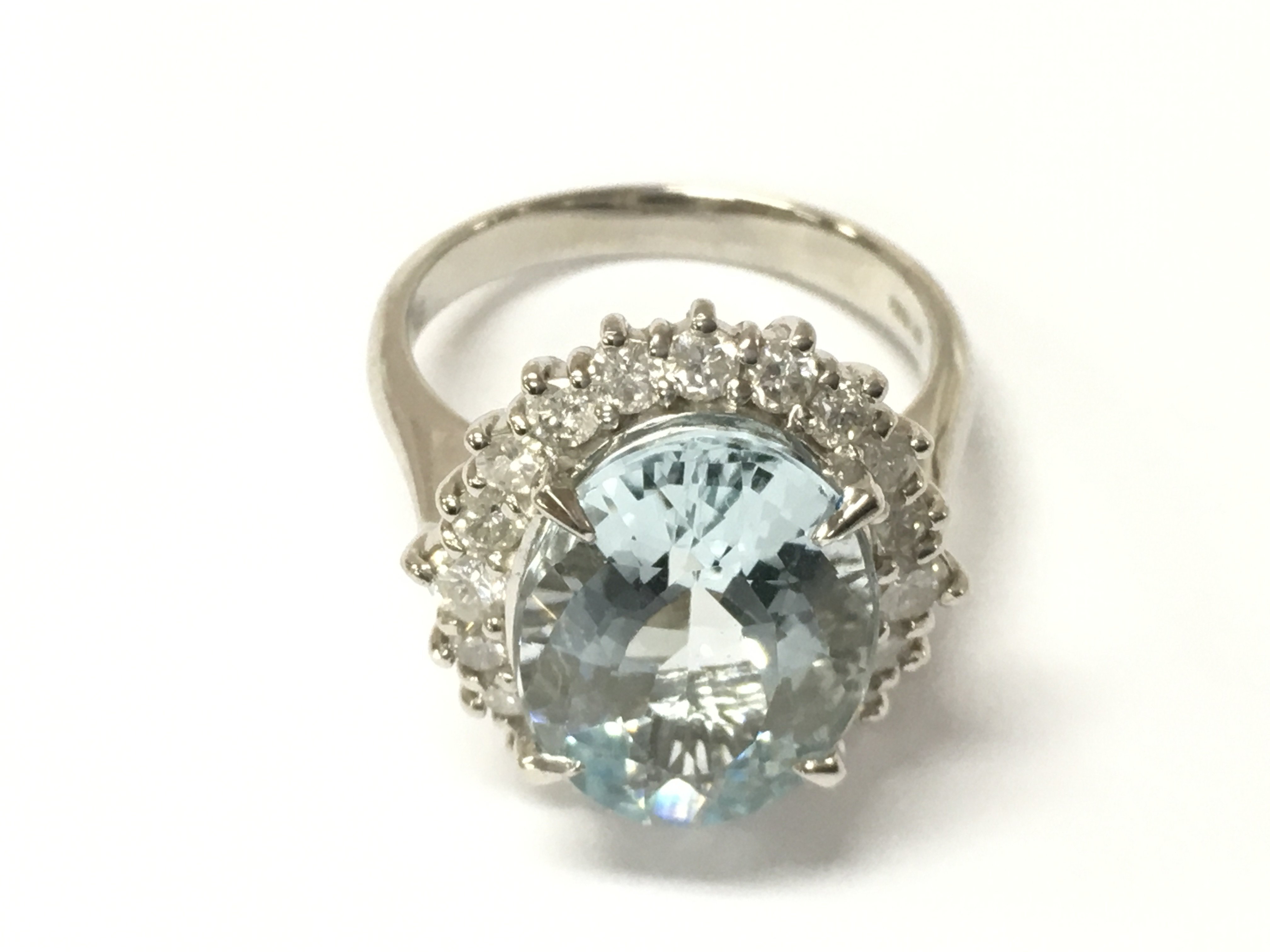 A platinum dress ring set with a large central oval aquamarine surrounded by RBC diamonds. Aquamarine 5.61ct eye clean. Diamonds 0.78ct G-H. With Gemologist report. Size L 1/2.