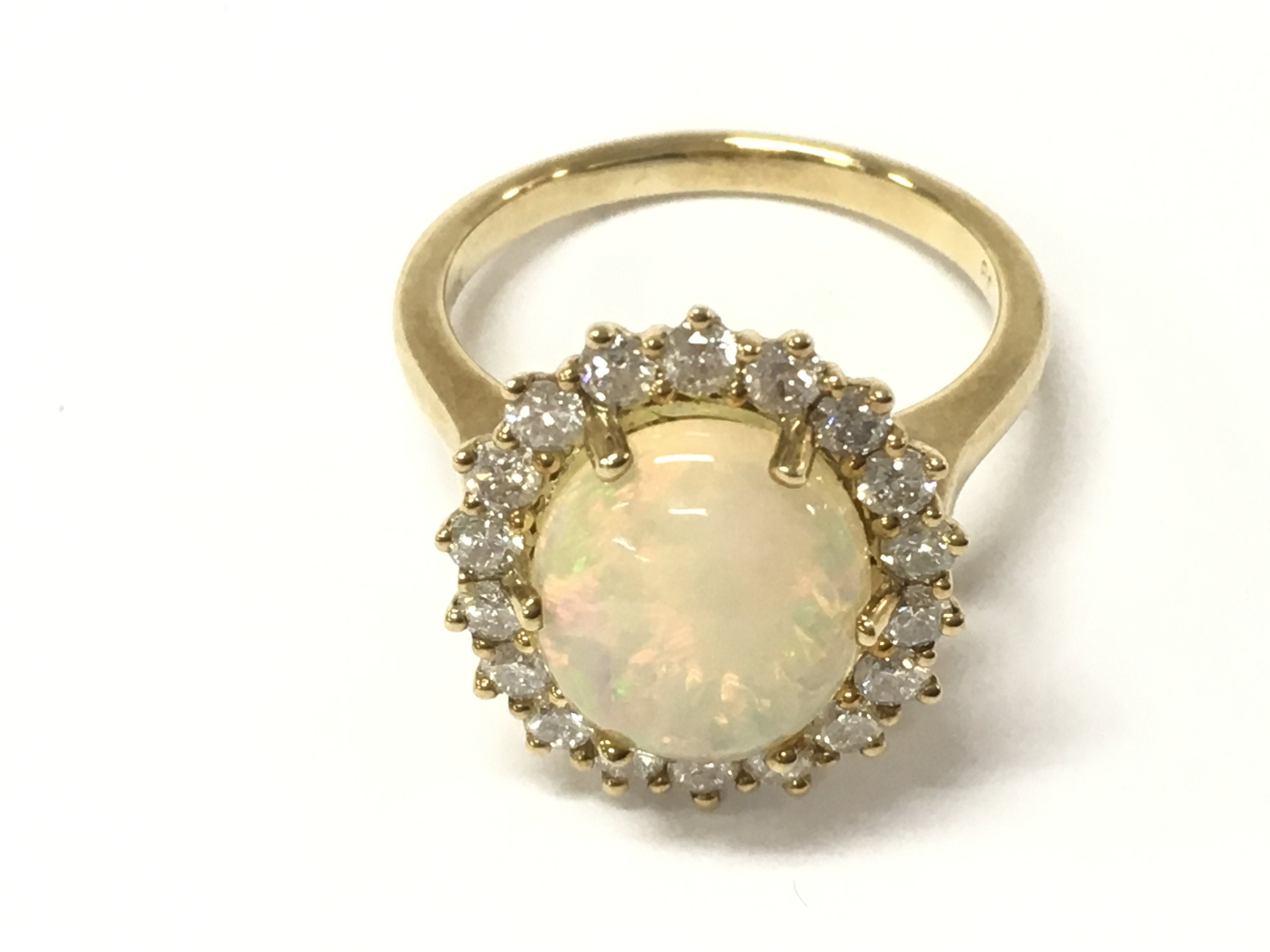 A 9ct yellow gold cluster ring set with an oval cabochon opal surrounded by diamond halo. Opal 2.69vt and diamonds 0.80ct approx. Size O