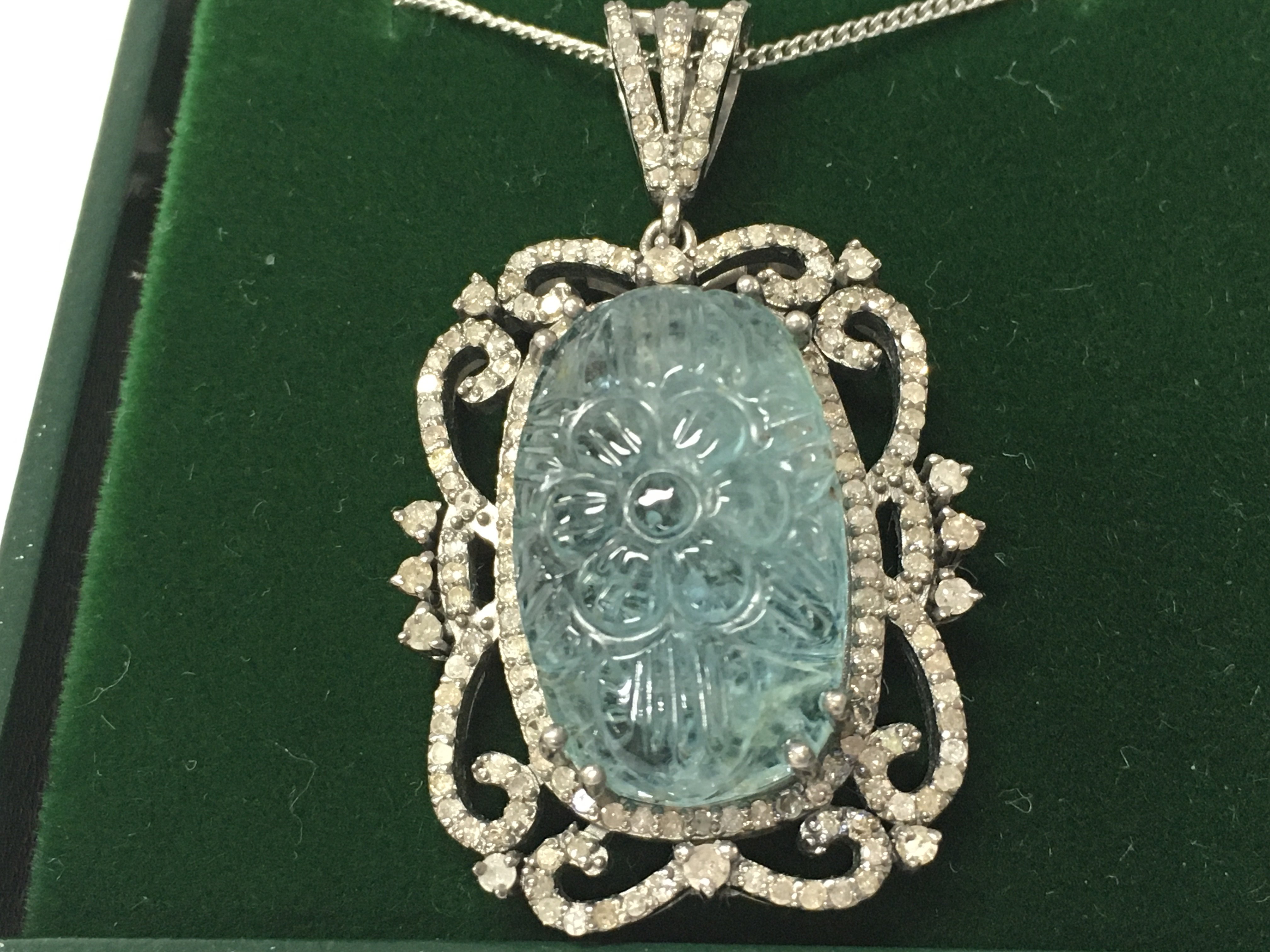 A silver pendant set with a large carved aquamarine and diamonds on a silver chain. Aquamarine 12.43ct diamonds 1.04ct Postage B