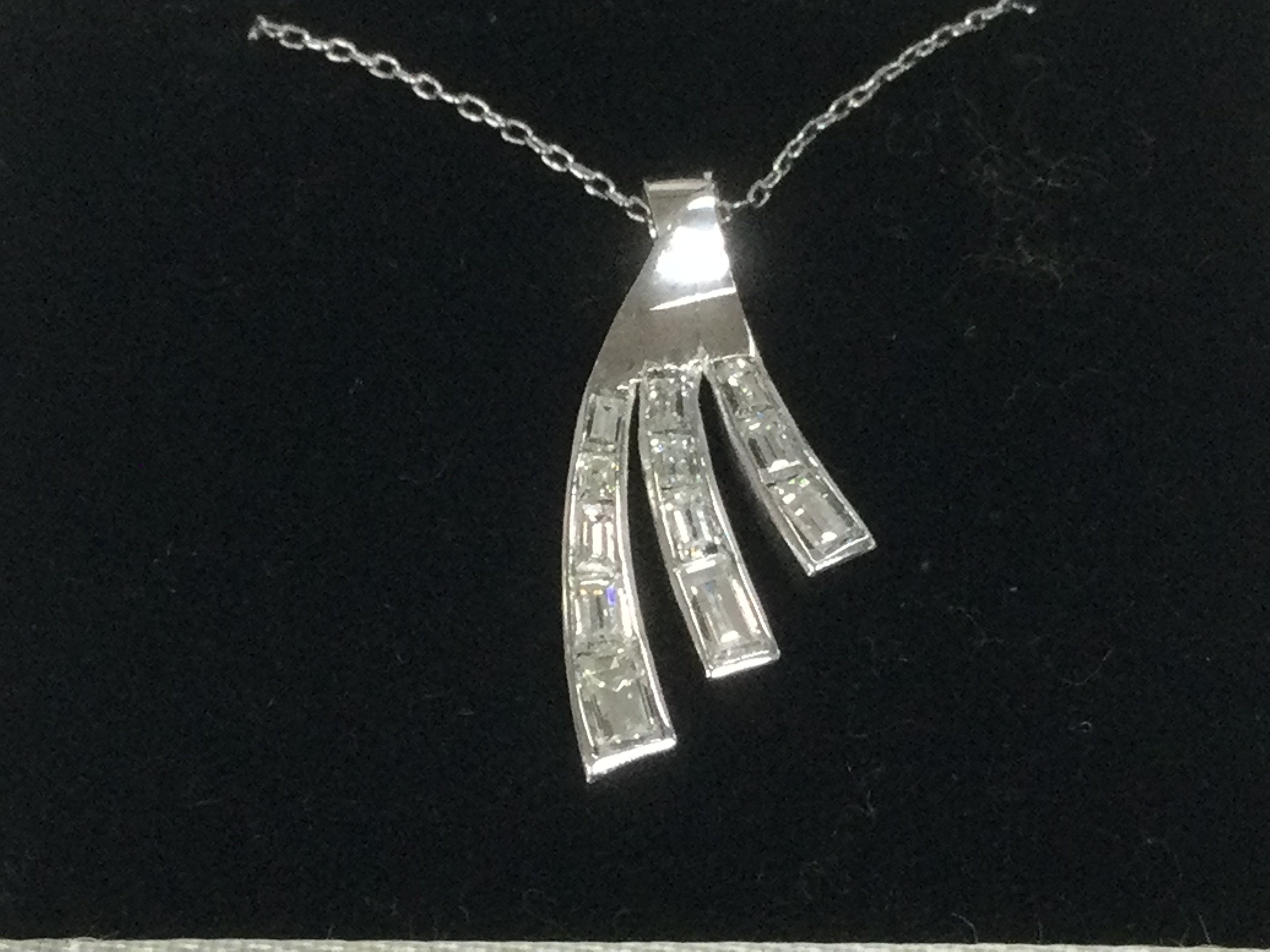 A modern design 18ct white gold pendant set with tapered baguette cut diamonds, approx 1ct. Shipping category A.