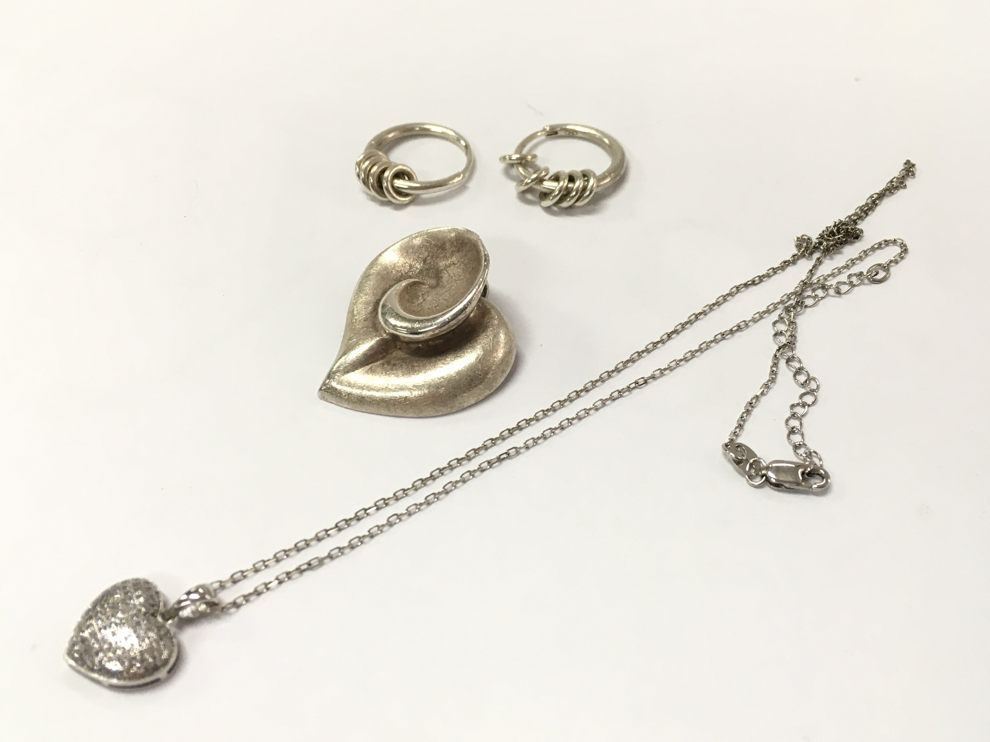 A silver group of jewellery including a silver floral pendant, earrings, heart pendant necklace. postage category A