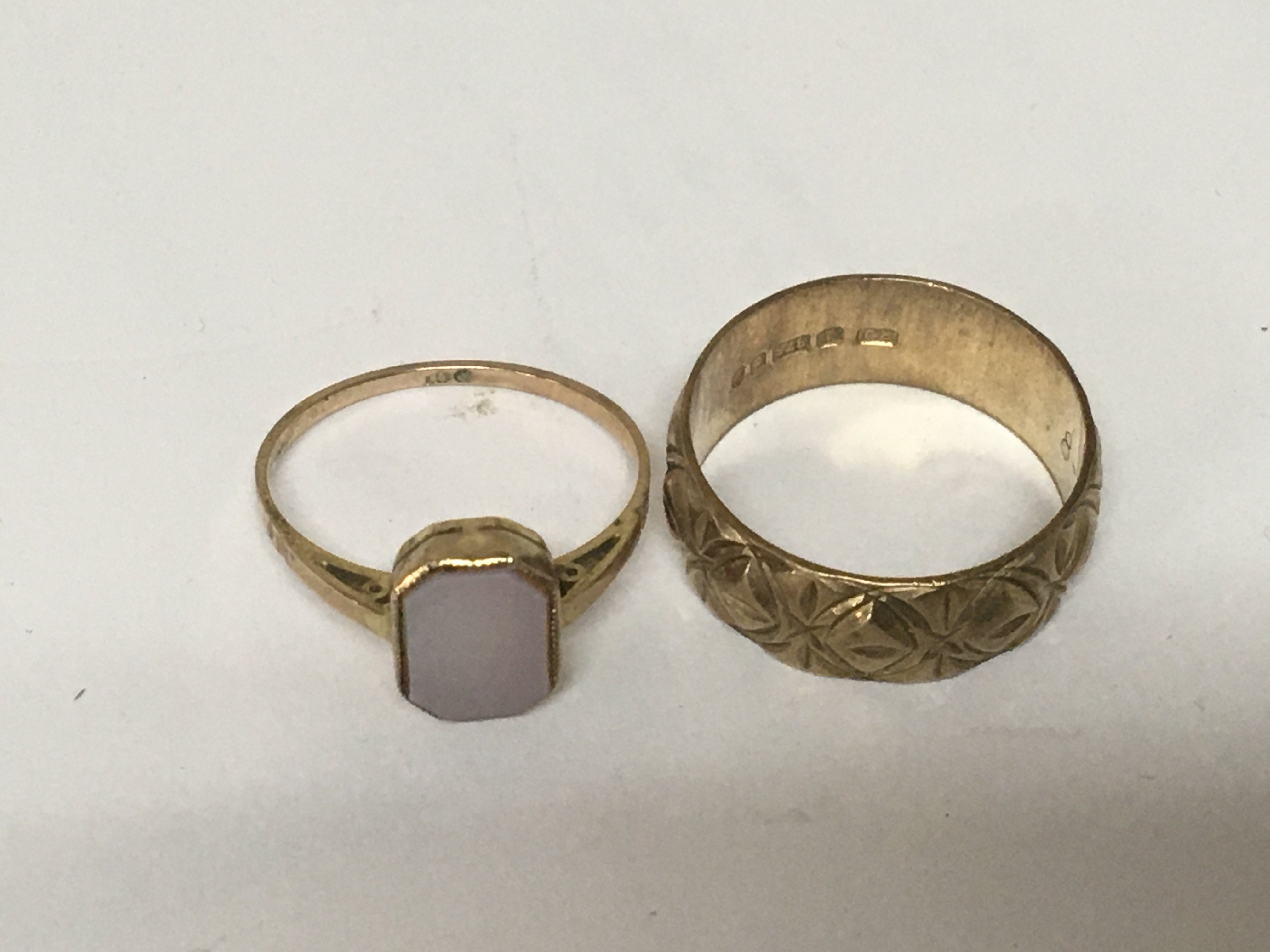 Two 9carat gold rings a wedding ring with a patterned edge a d one other ring set with a polished stone. Weight 5.4g approximately. (2)
