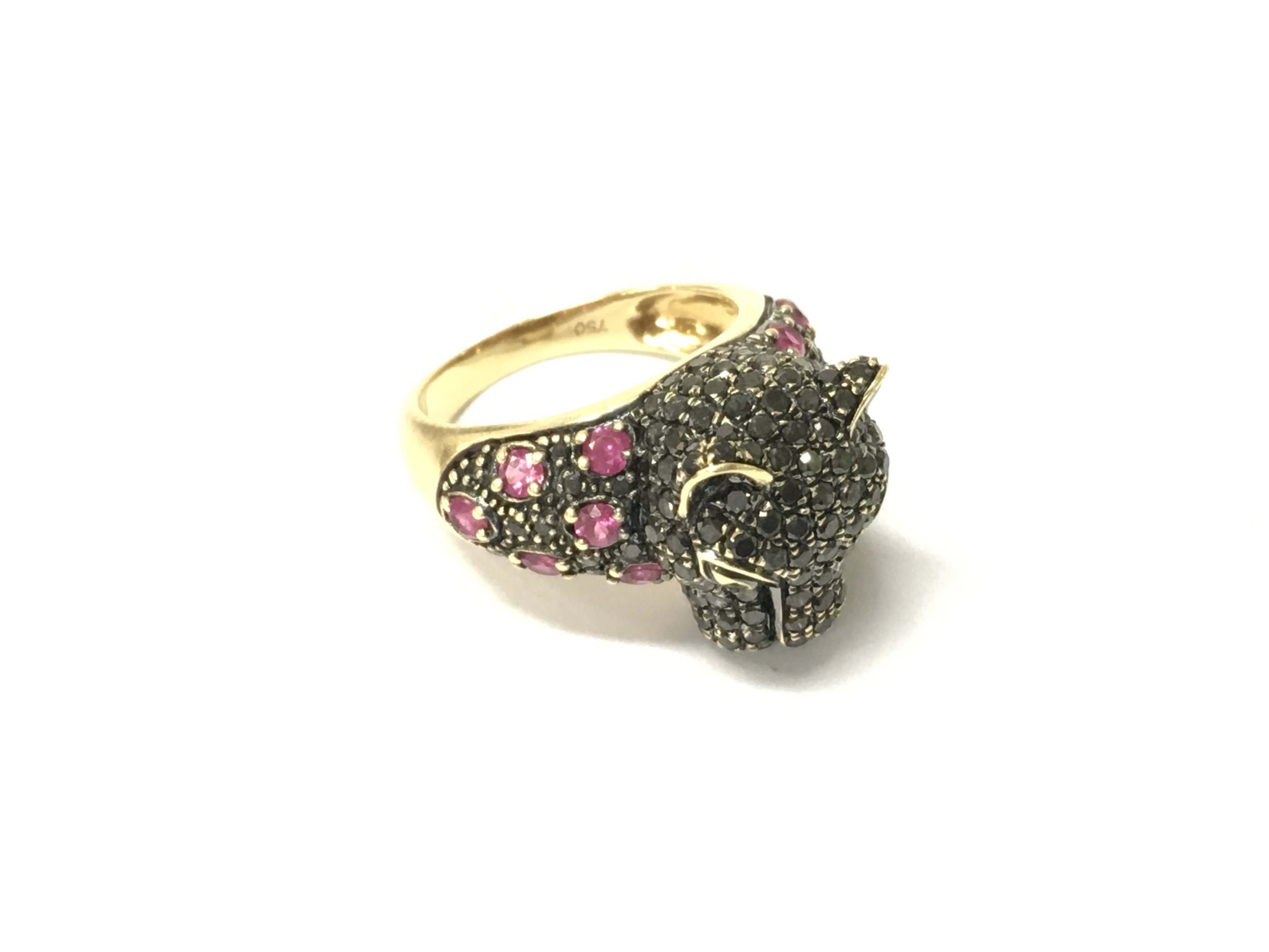 A stone set panther head ring stamped 750 set with black diamonds and rubies, Approx weight 6.99 grams. Size L 1/2.