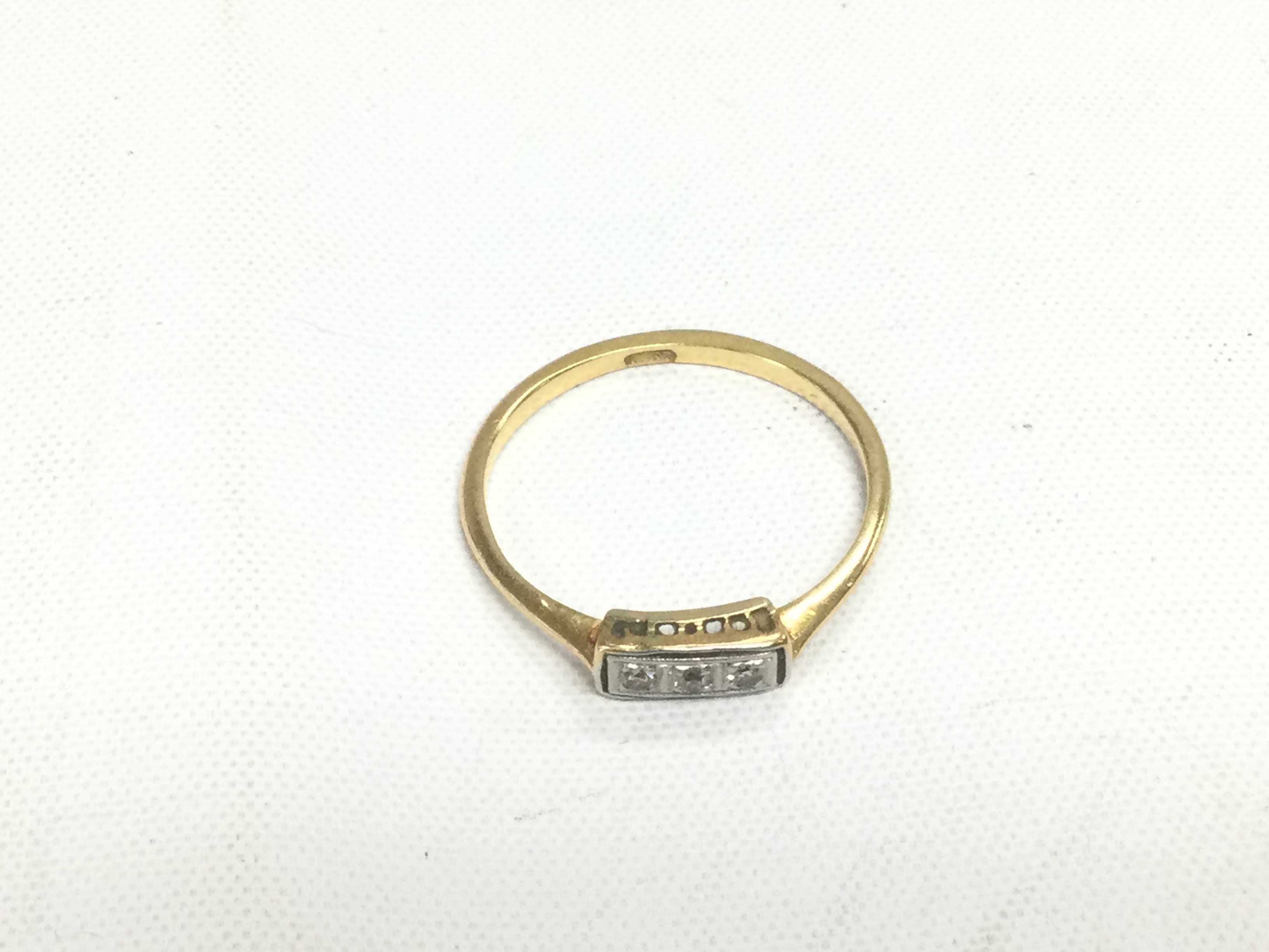 A gold ring set with three small diamonds, approx 2.3g and approx size T. Shipping category A.