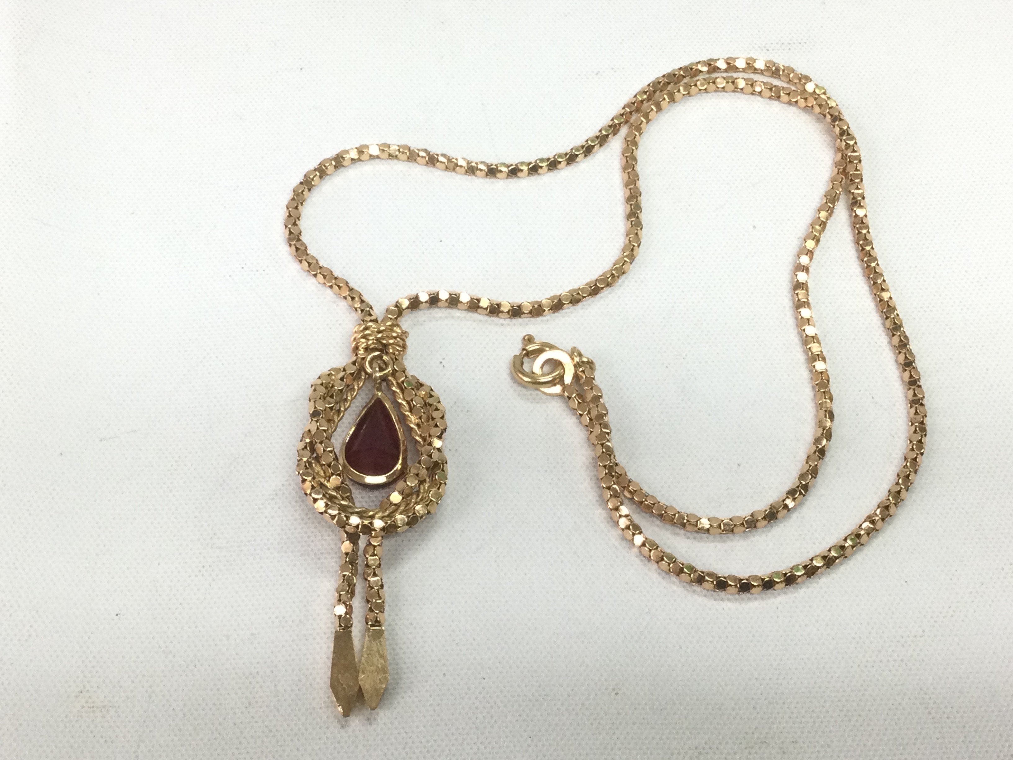 A gold pendant and chain marked 750 but tested as 14k. Pendant set ith a ruby, approx 9.3g. Shipping category A.