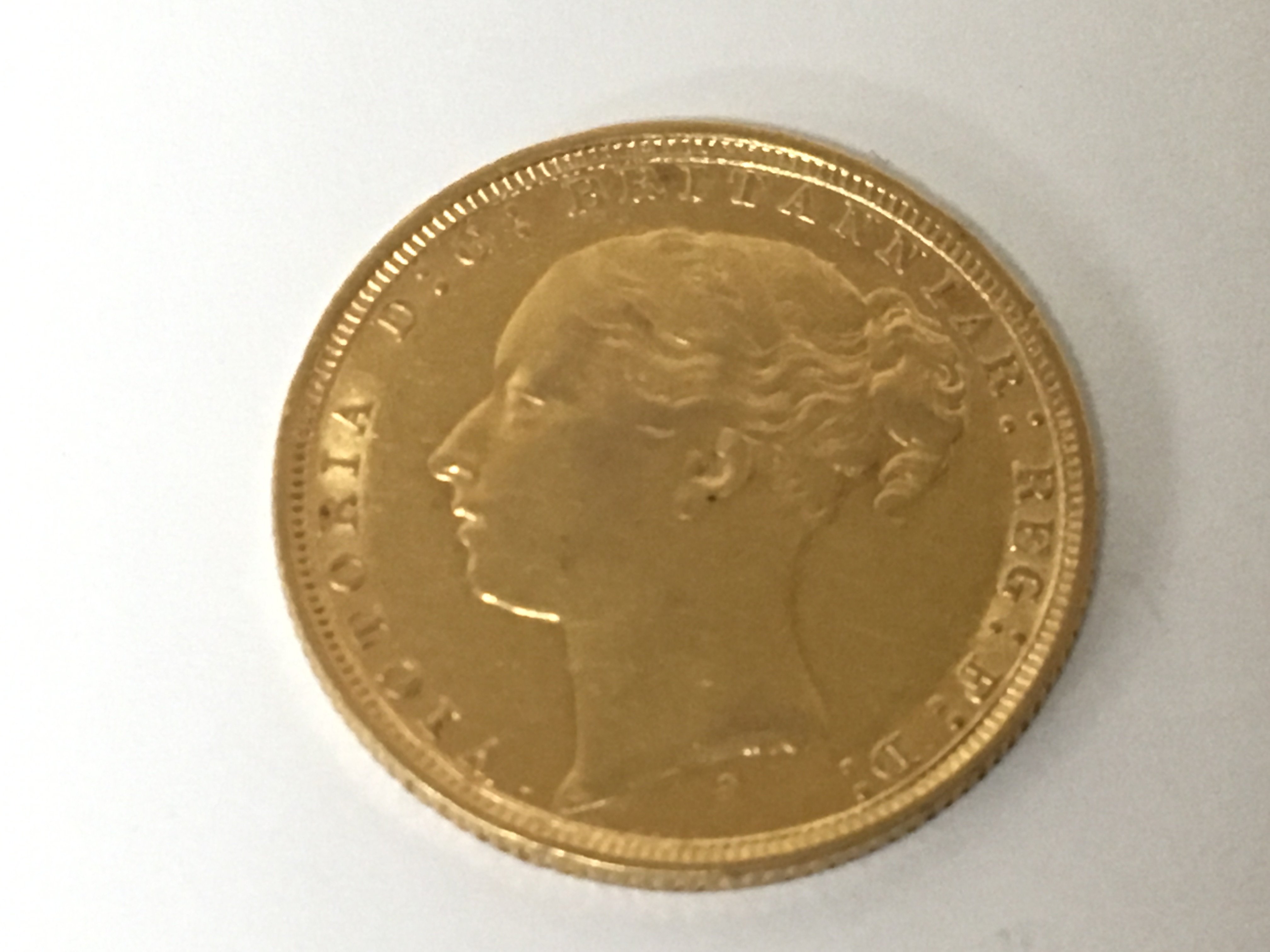 A Victorian 1884 gold sovereign with a young side profile portrait of Queen Victoria.
