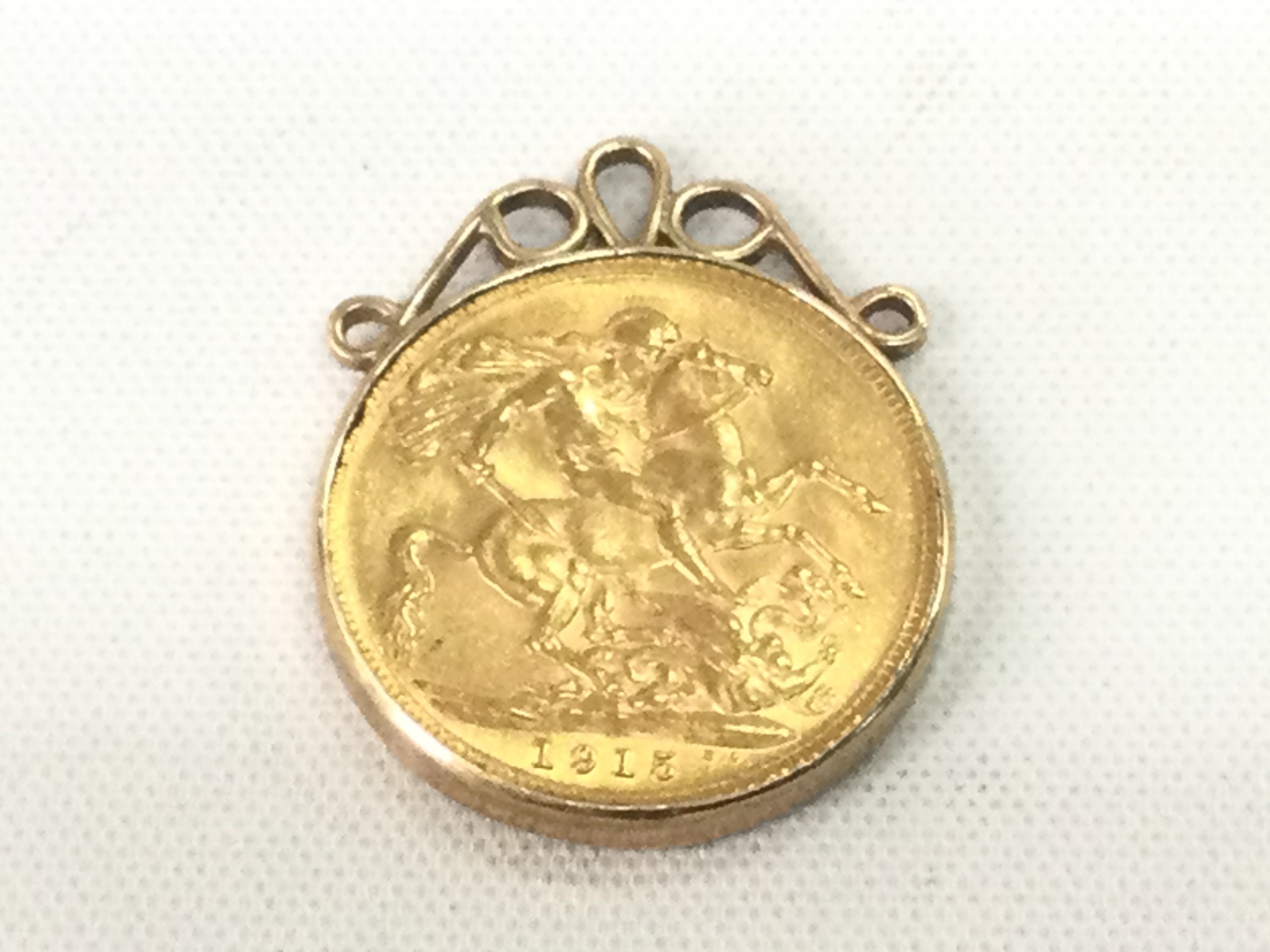 A 1915 gold sovereign in a gold mount, approx 9.7g. Shipping category A.