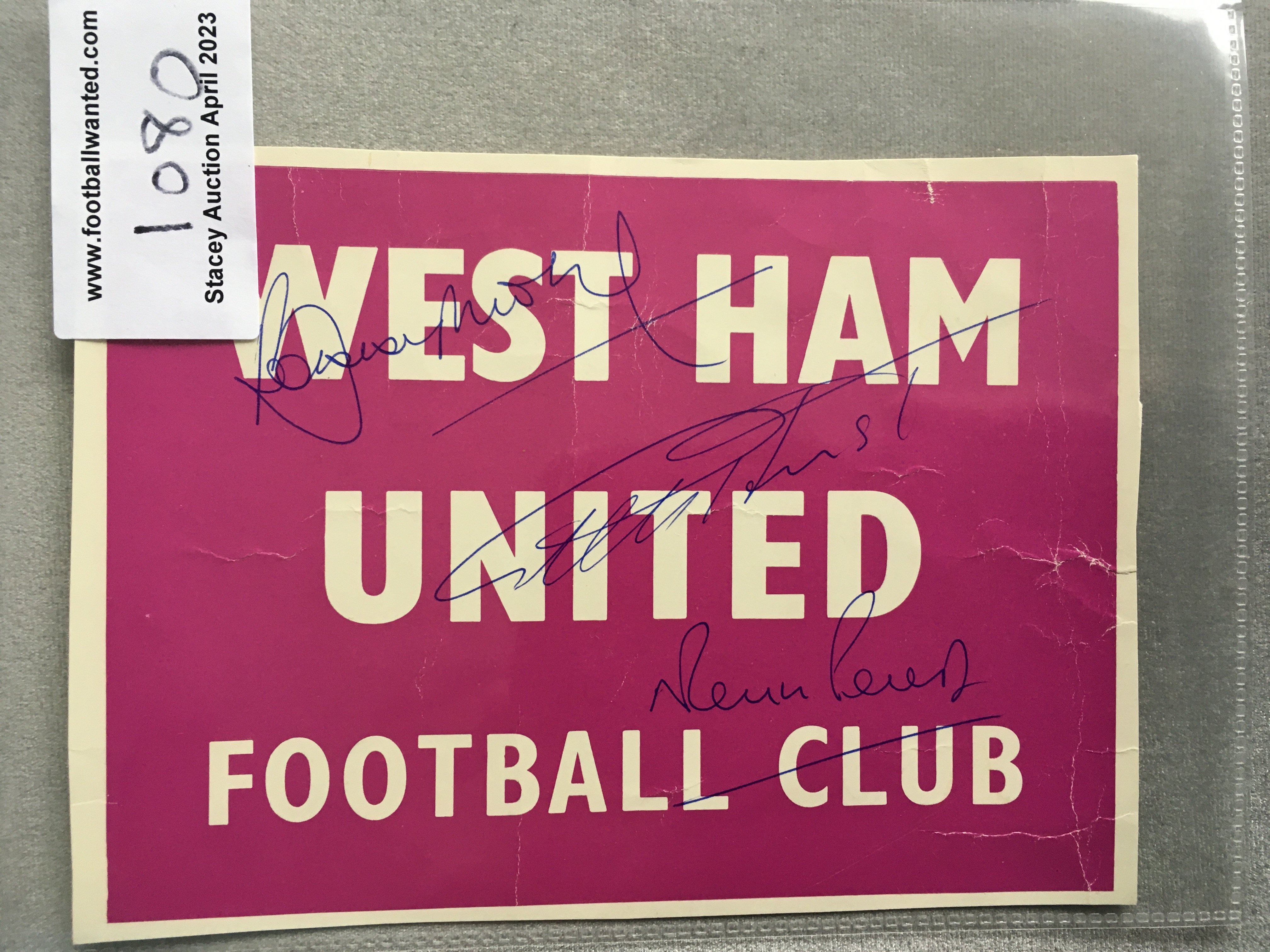 Bobby Moore Double Signed West Ham Sign: Pink and white card stating West Ham United Football Club. Hand signed in biro to front by World Cup winners Hurst Moore and Peters and to rear clearly on white background.