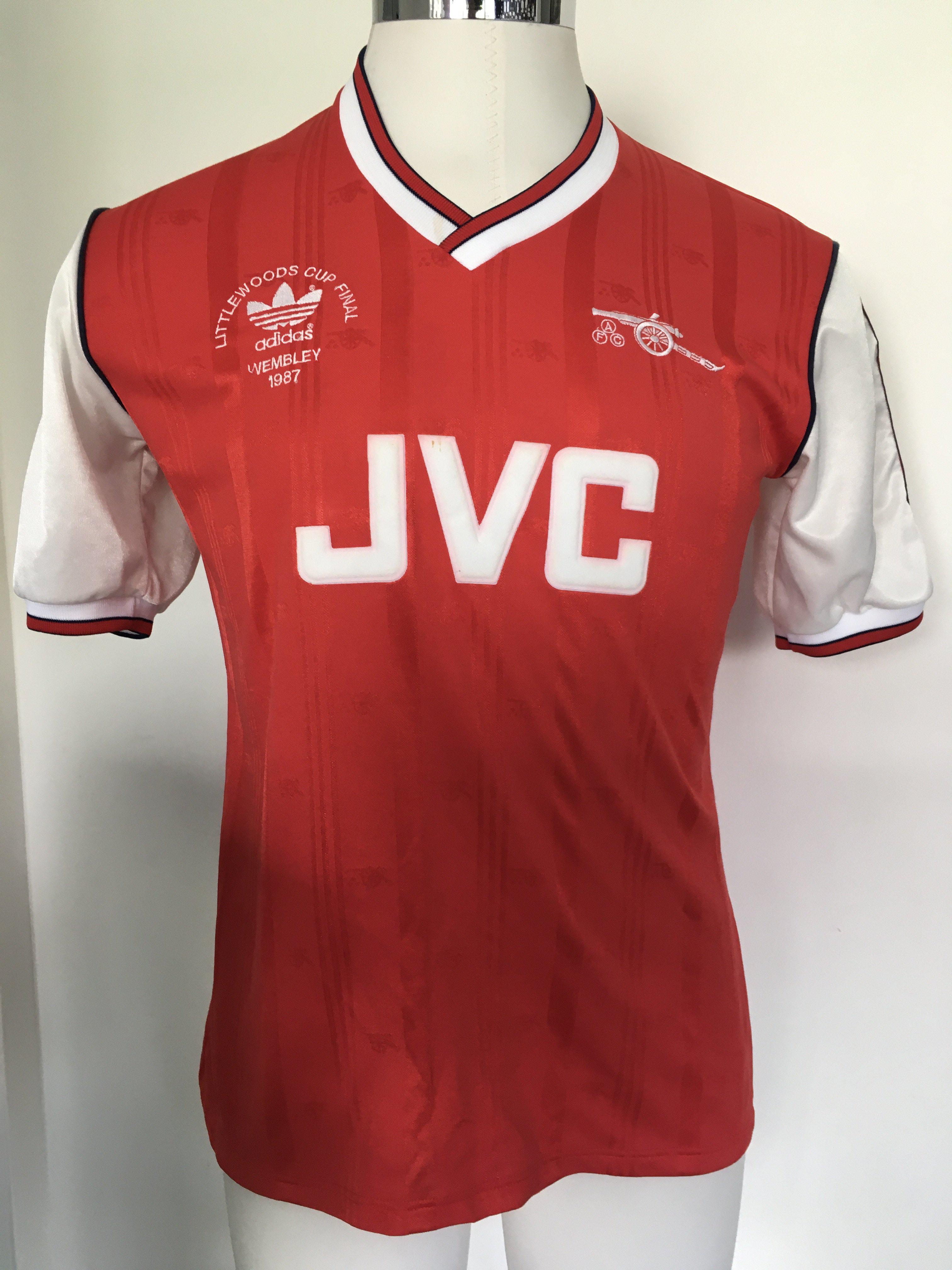 Arsenal 1987 League Cup Final Match Worn Football Shirt: Red short sleeve number 3 shirt with Littlewoods Cup Final 1987 Wembley 1987 under Adidas logo all embroidered. Framed white card reads This was the shirt that I wore when Arsenal won the Littlewoods Cup in 1987 against Liverpool. I was the captain and we won 2-1 signed by Kenny Sansom. Also comes with two signed press photos of Sansom wearing the shirt holding the cup on the pitch.