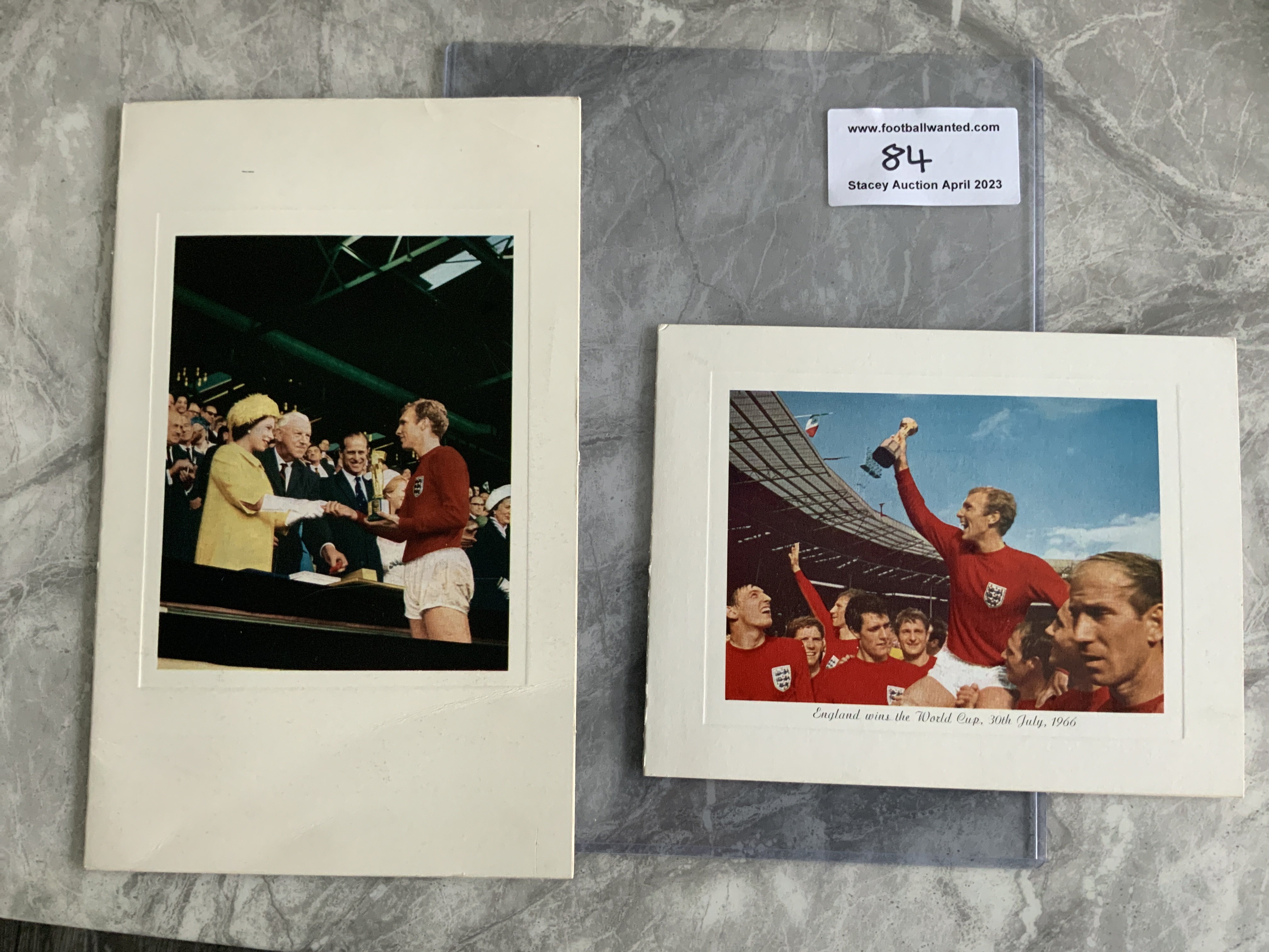 1966 England World Cup Winners Official Christmas Cards: Both FIFA and the English FA used Christmas cards depicting Bobby Moore with the World Cup. FIFA opted for Bobby shaking hands with the Queen after receiving the World Cup and the FA went for Bobby being held aloft with team mates whilst holding the cup. Both unwritten with Christmas wishes printed and dated December 1966. Rare and in very good condition. FIFAs card has been signed by president Stanley Rous and secretary Helmet Kaser which we believe are printed autographs. (2)