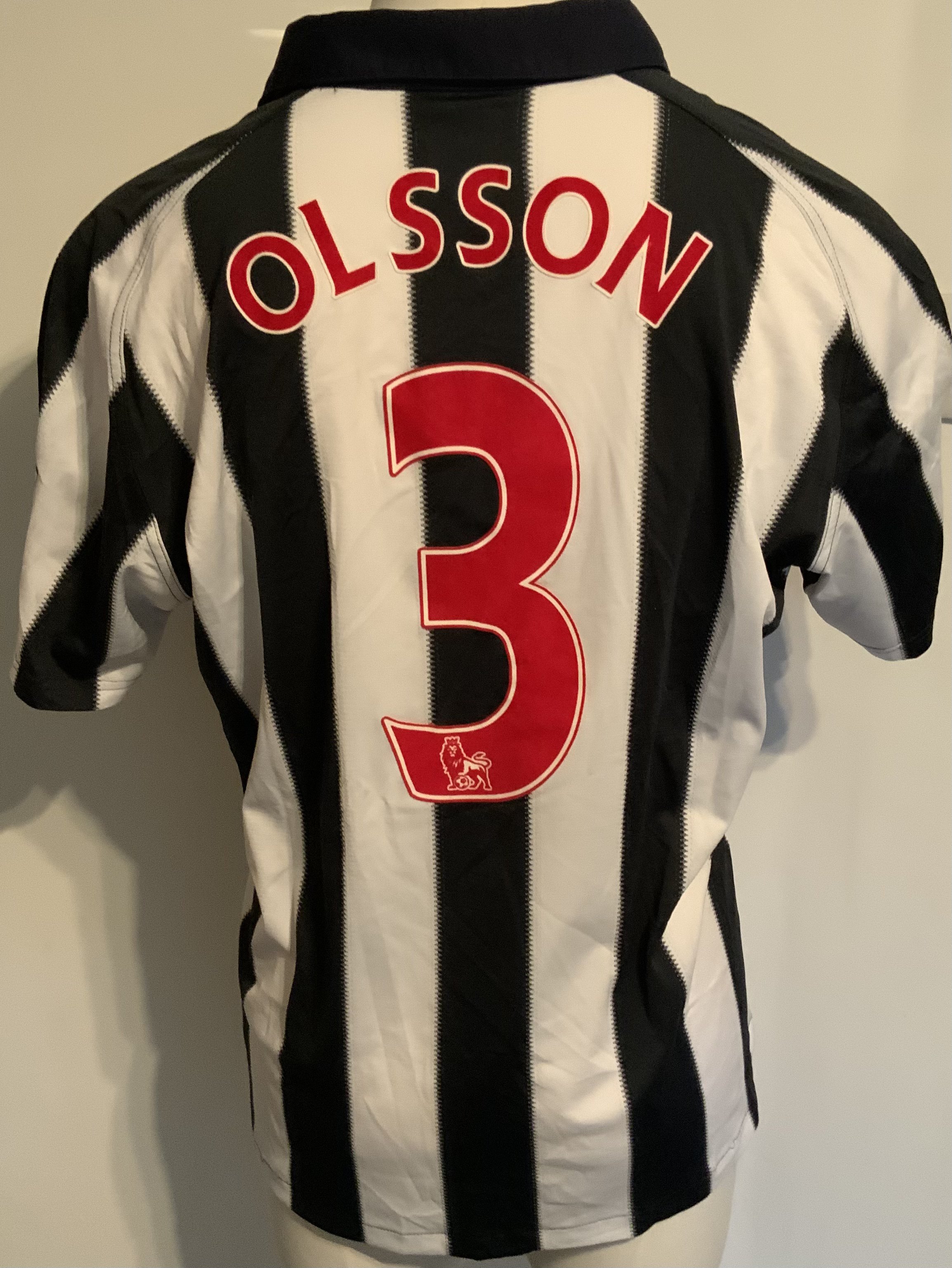 West Brom 2010 - 2011 Match Worn Football Shirt: Worn v Arsenal on 19 3 2011. Home short sleeve with Premiership badging to arms and number 13 Olsson to rear.