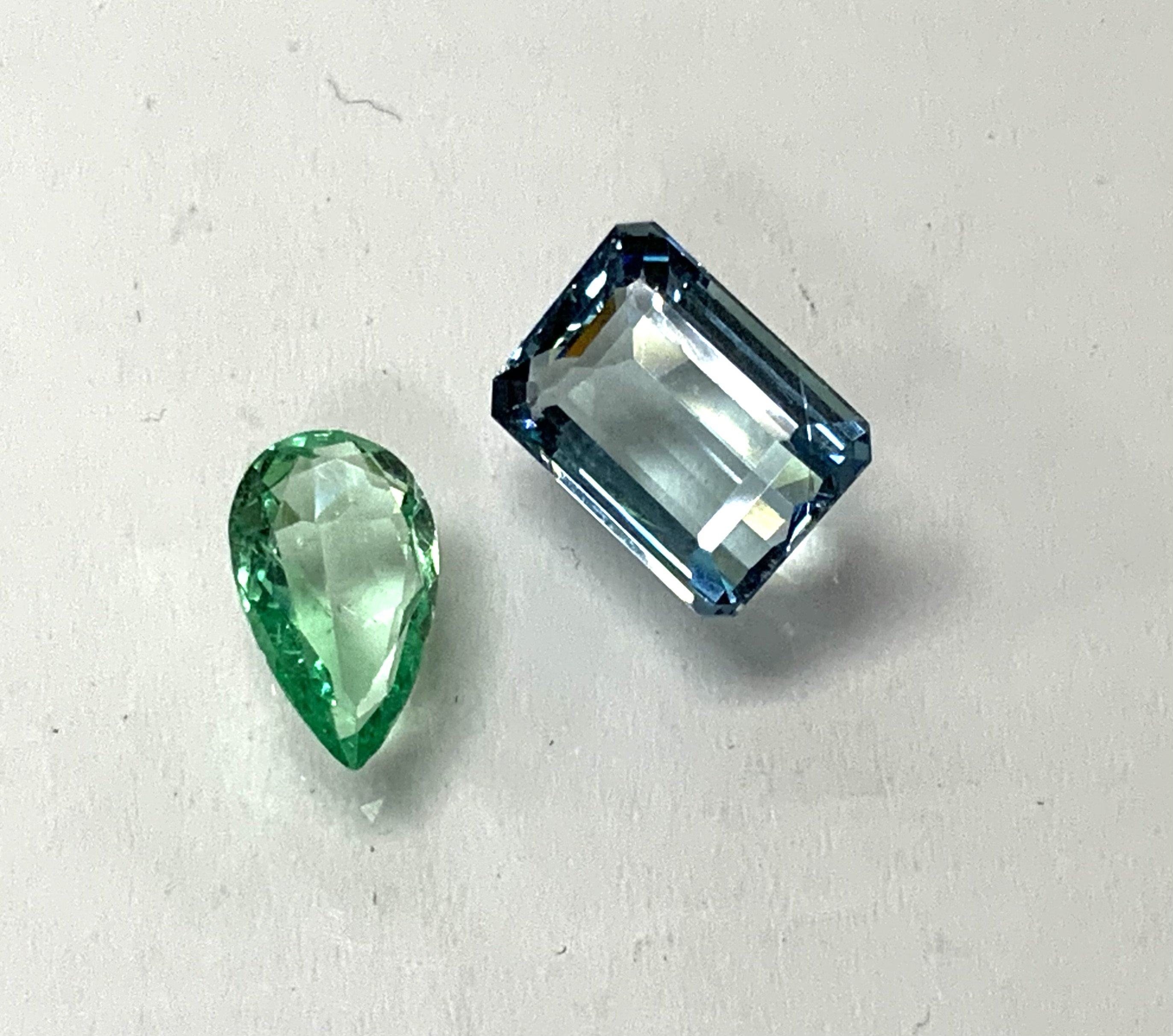 A loose emerald cut aquamarine 0.84g together with a loose pear shaped emerald 0.28g. (A)