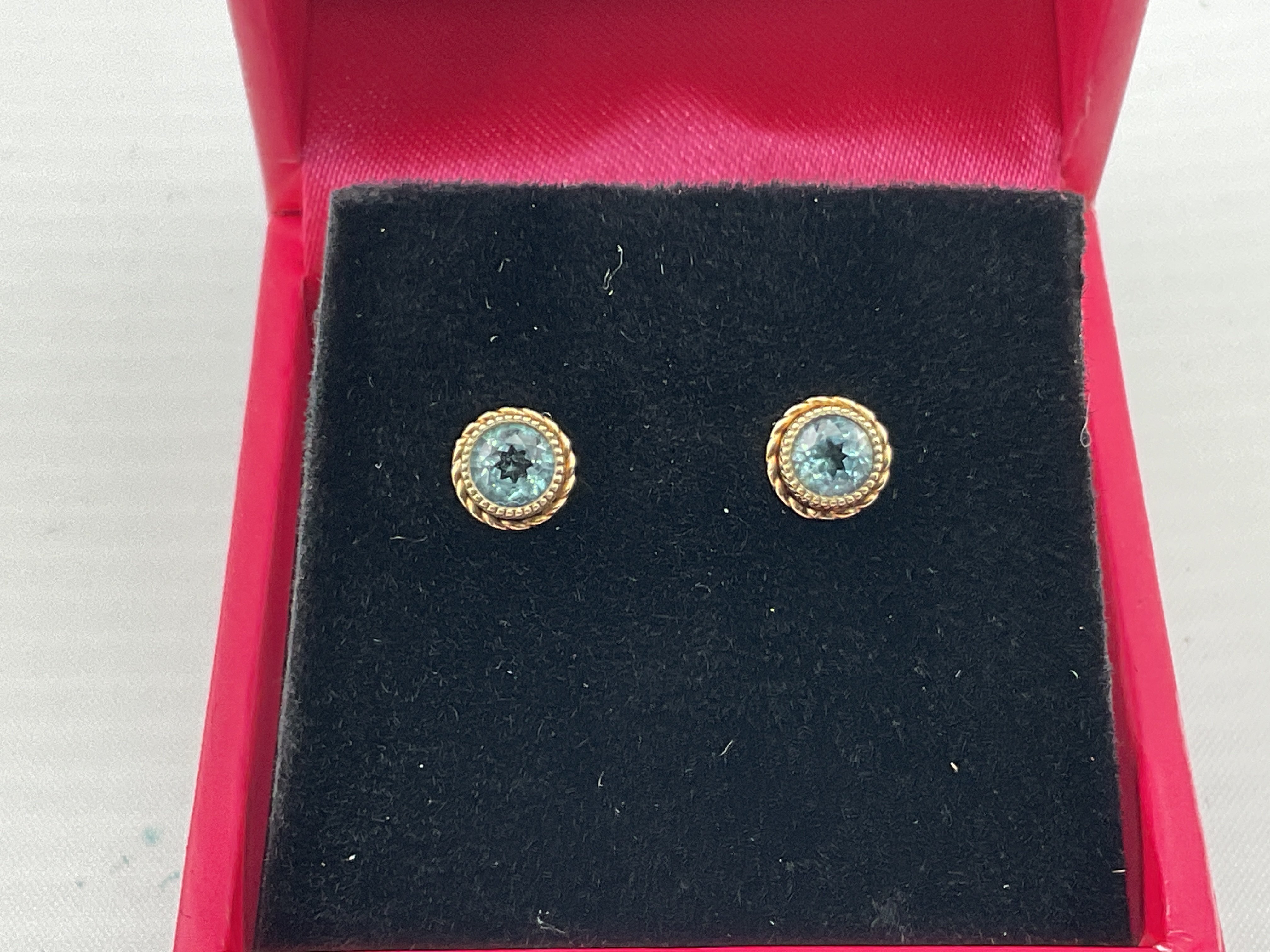 A pair of 9ct gold studs set with blue topaz. Postage category A.