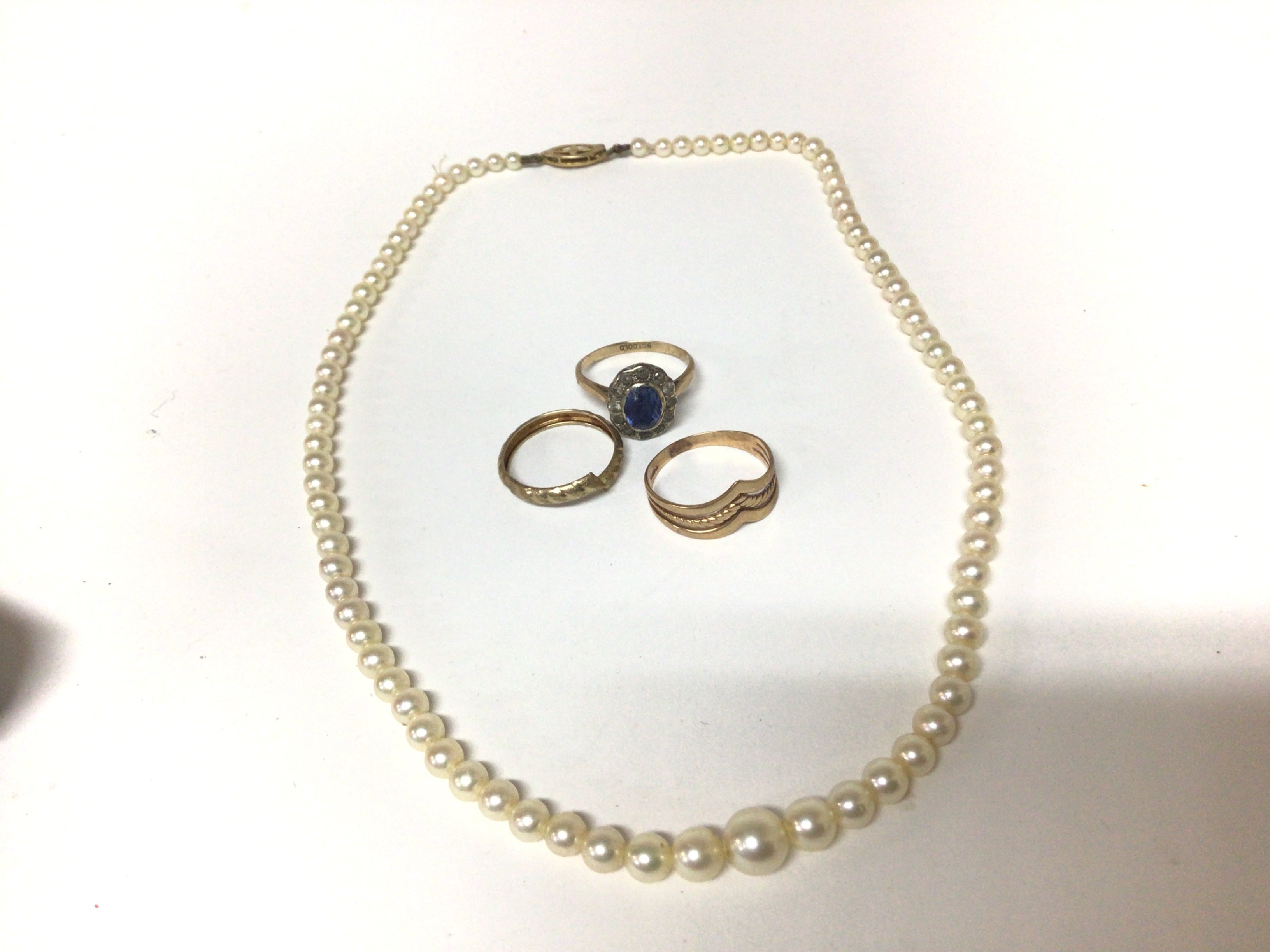 A 9carat gold ring set with a sapphire two other gold rings and a cultured pearl necklace with a 9carat gold clasp.
