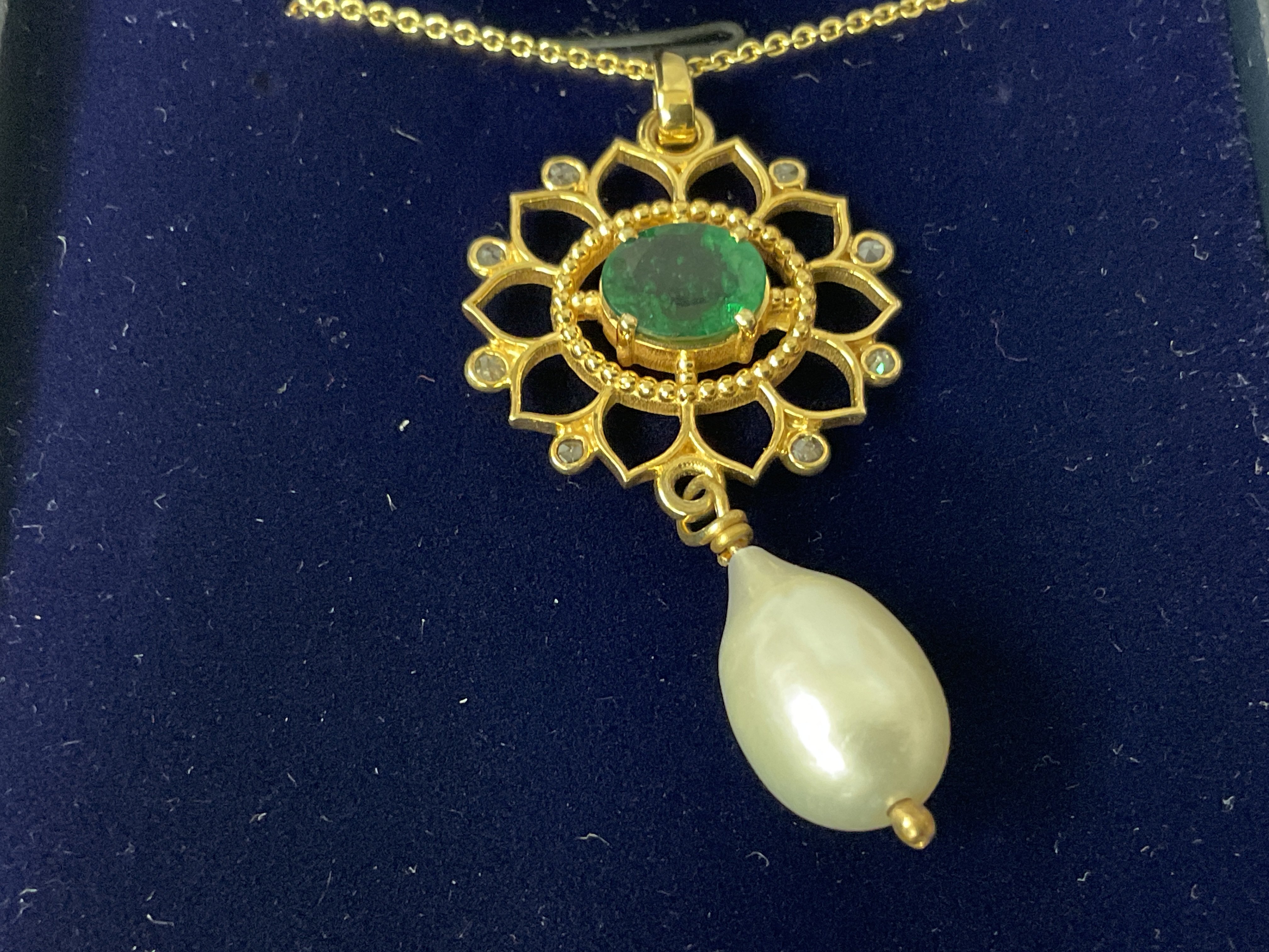 Fancy pendant in yellow metal set with diamonds, an oval metal emerald with a suspended pearl on a gold plated silver chain, boxed. Emerald 1.00ct approx. Diamonds 0.08ct approx. Postage category A.