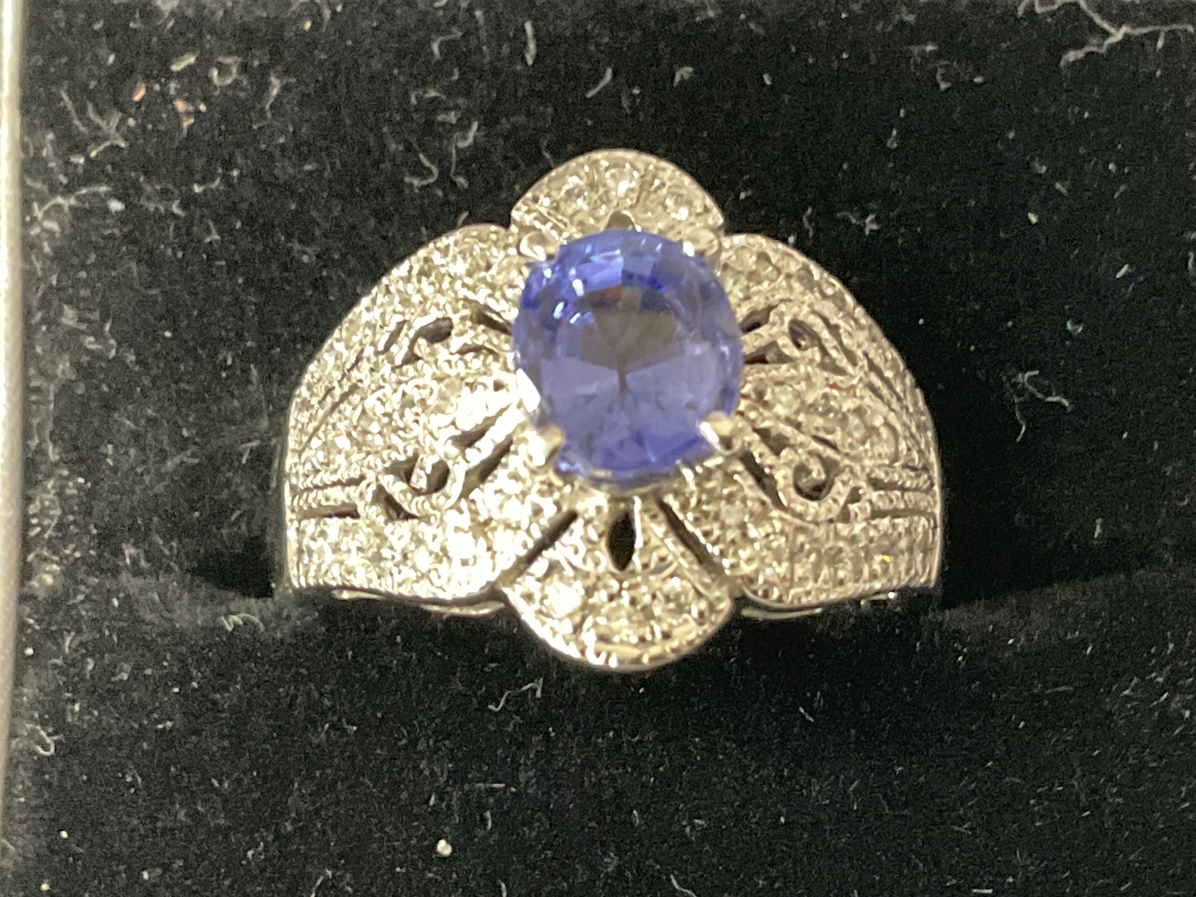 Stylish platinum ring with an oval tanzanite and inter pierced ornate diamond surround, boxed. Tanzanite 1.52ct. Diamonds 0.28ct. Ring size approx M. Postage category A.