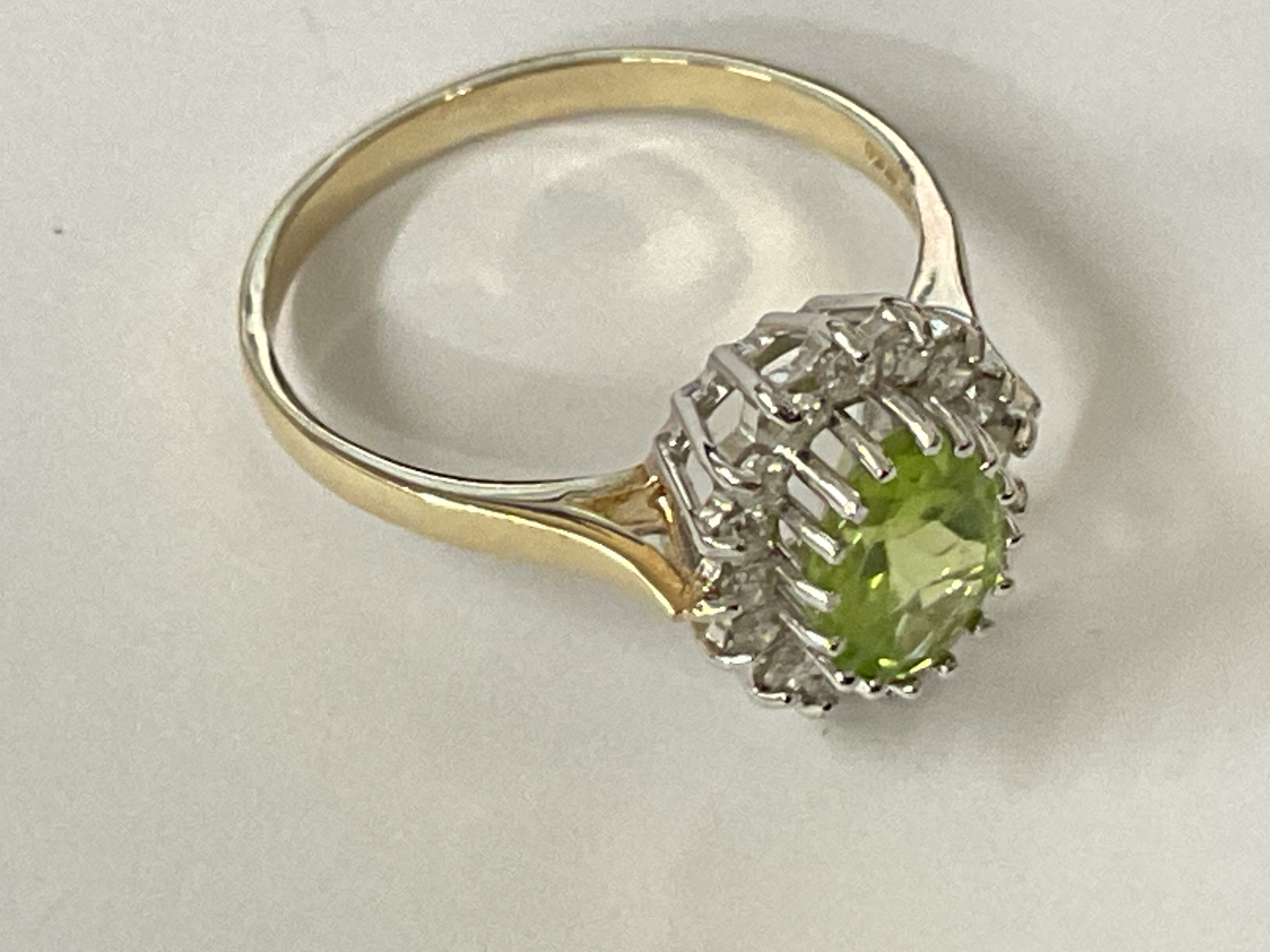 9ct yellow and white gold cluster ring set with an oval cut peridot and RBC diamonds. Ring size approx N/O. Postage category A.