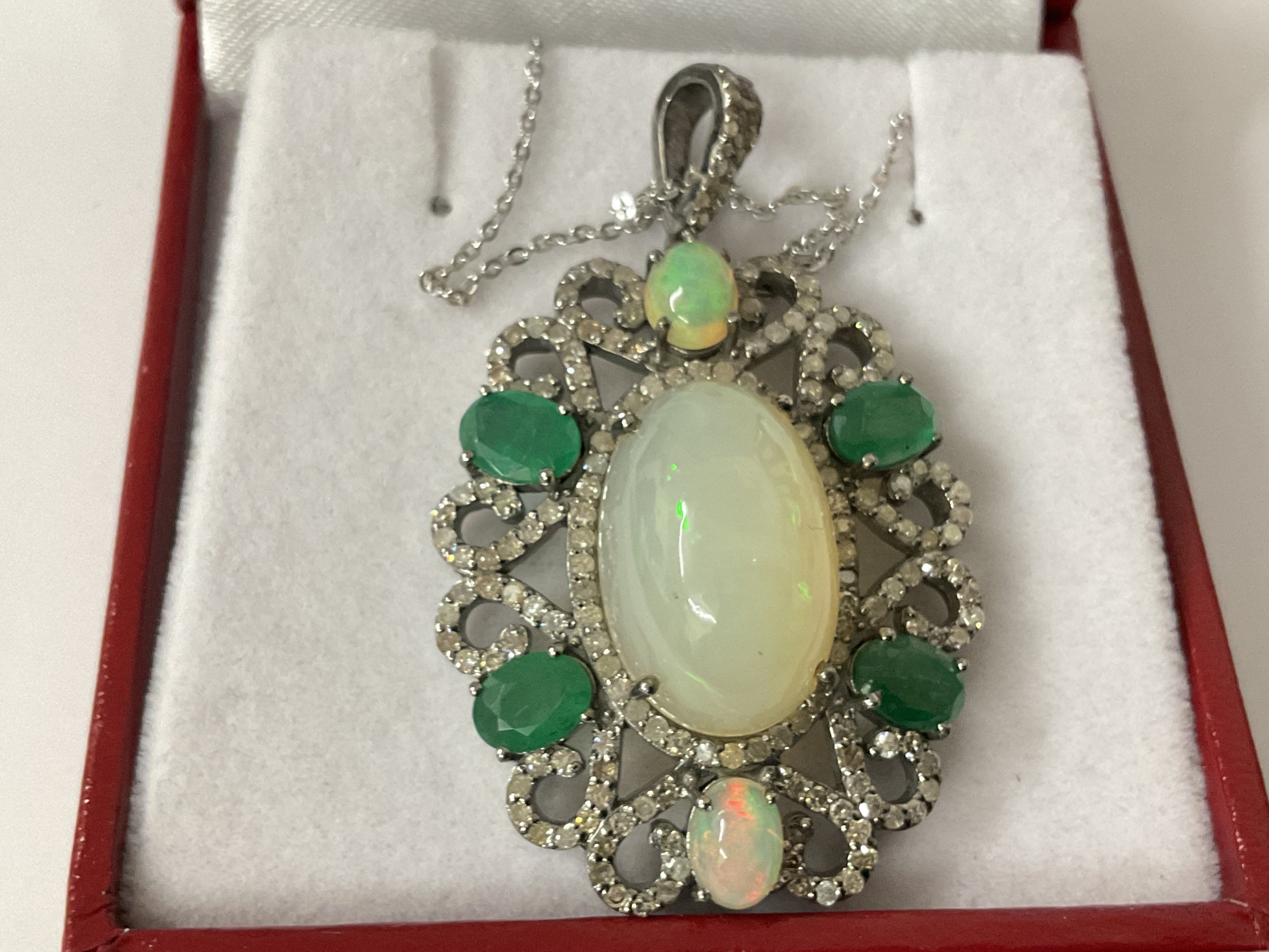 Silver floral style pendant set with opals, diamonds and emeralds on a silver chain, boxed. Opals 11.18ct. Emeralds 2.88ct. Diamonds 2.00ct. Postage category A.