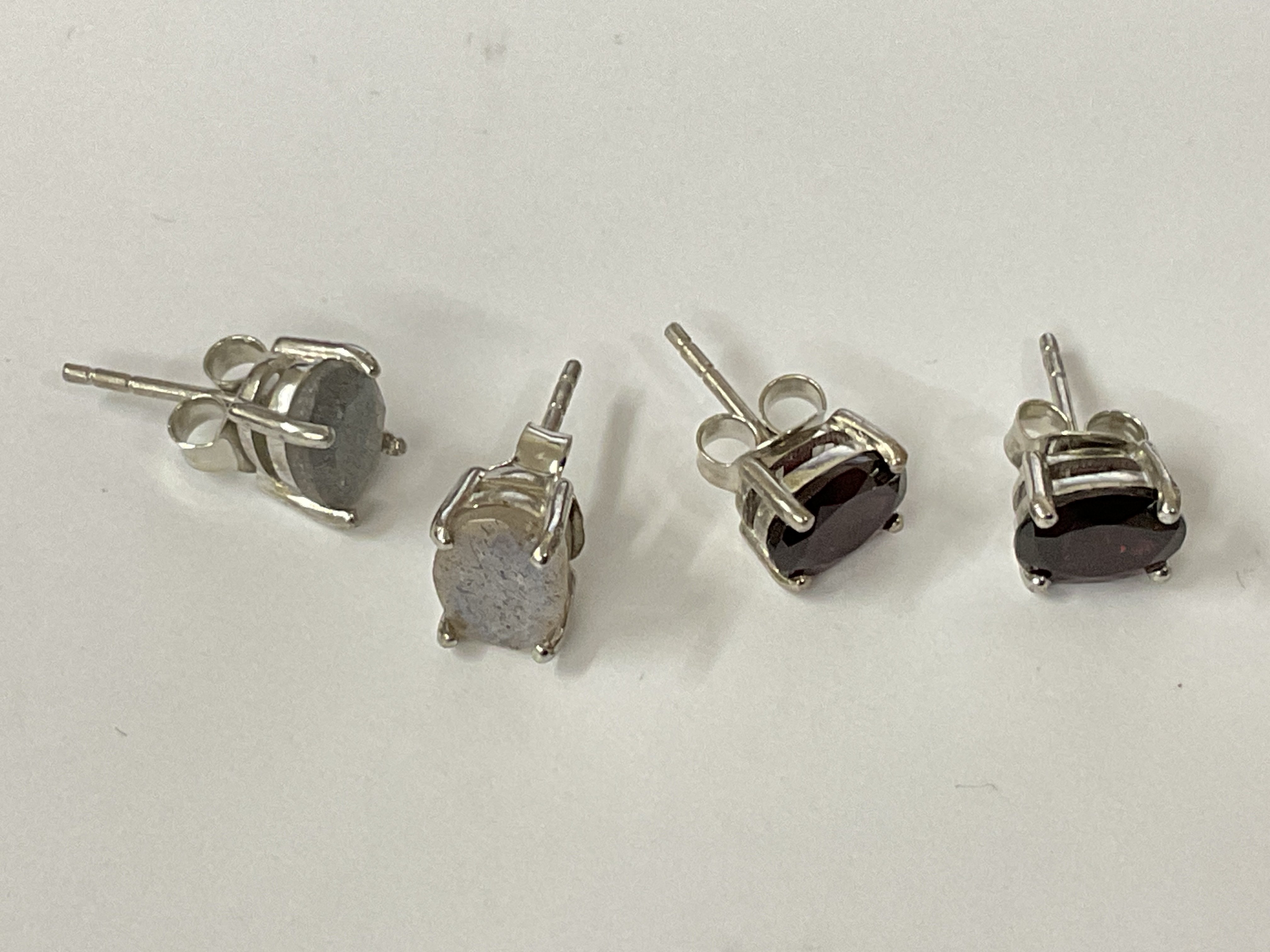 Two pairs of oval silver studs, one set with rhodolite garnet and the other set with labradorite. Postage category A.