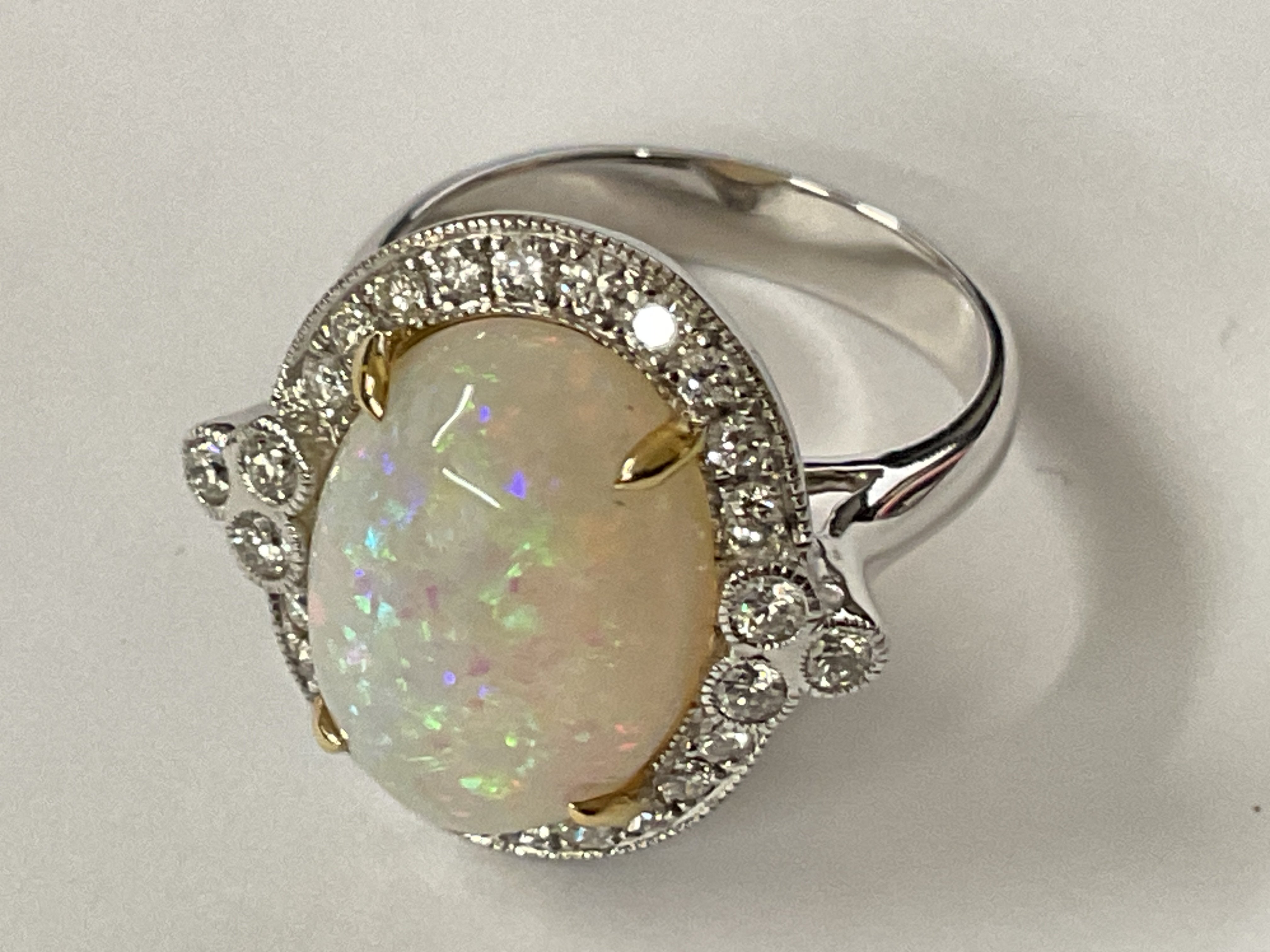 18ct white and yellow gold ring set with an oval cabochon Opal surrounded by RBC diamonds in a beaded setting. Opal 5.22ct. Diamonds 0.53ct. Ring size approx M/N. Postage category A.
