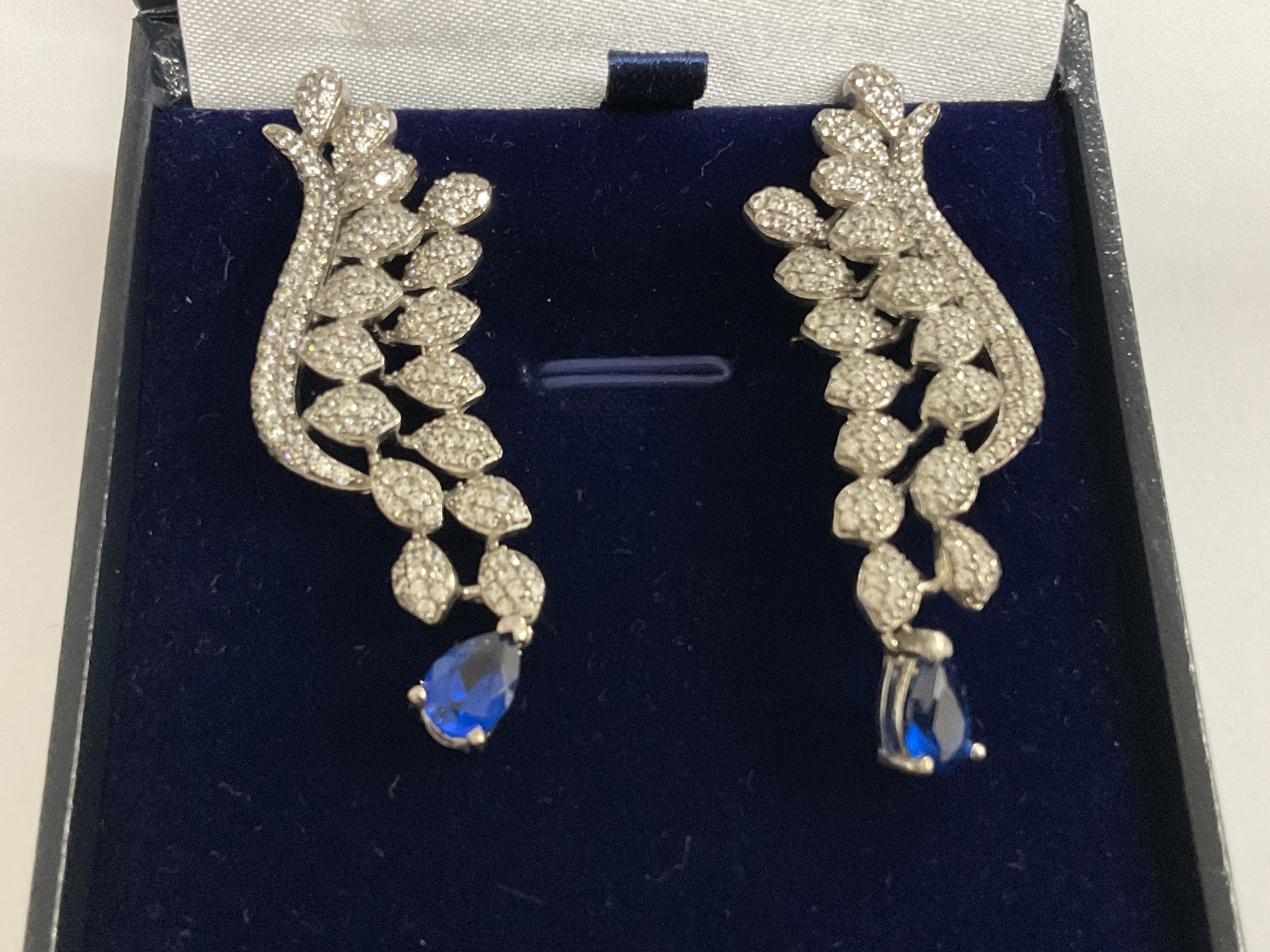 Pair silver fancy long drop earrings set with clusters of white cubic zirconia, and suspended pear shaped blue cubic zirconia, boxed. Postage category A.
