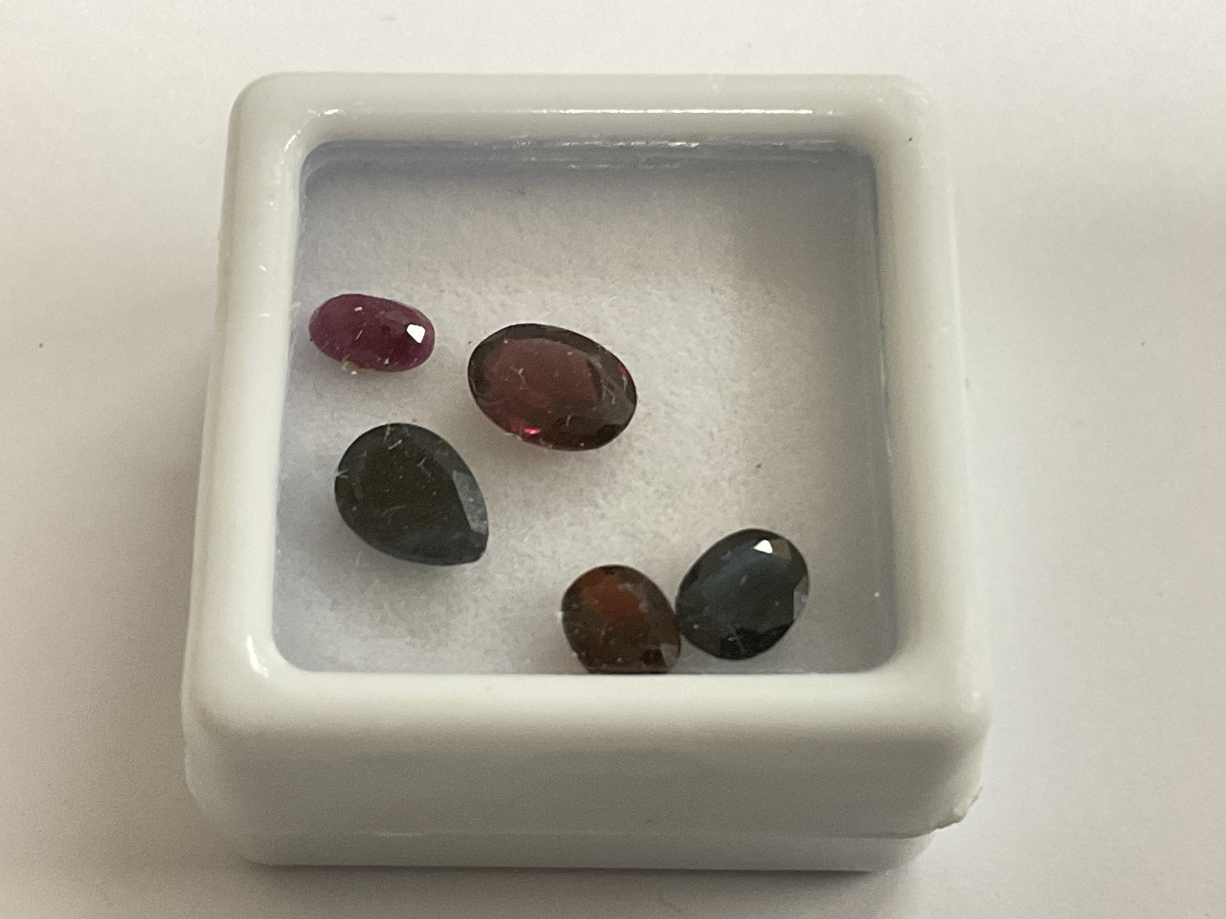 Parcel of loose gemstones, including sapphire, ruby and garnet, boxed. Sapphires 1.47ct. Ruby 0.37ct. Garnet 1.39ct. Postage category A.