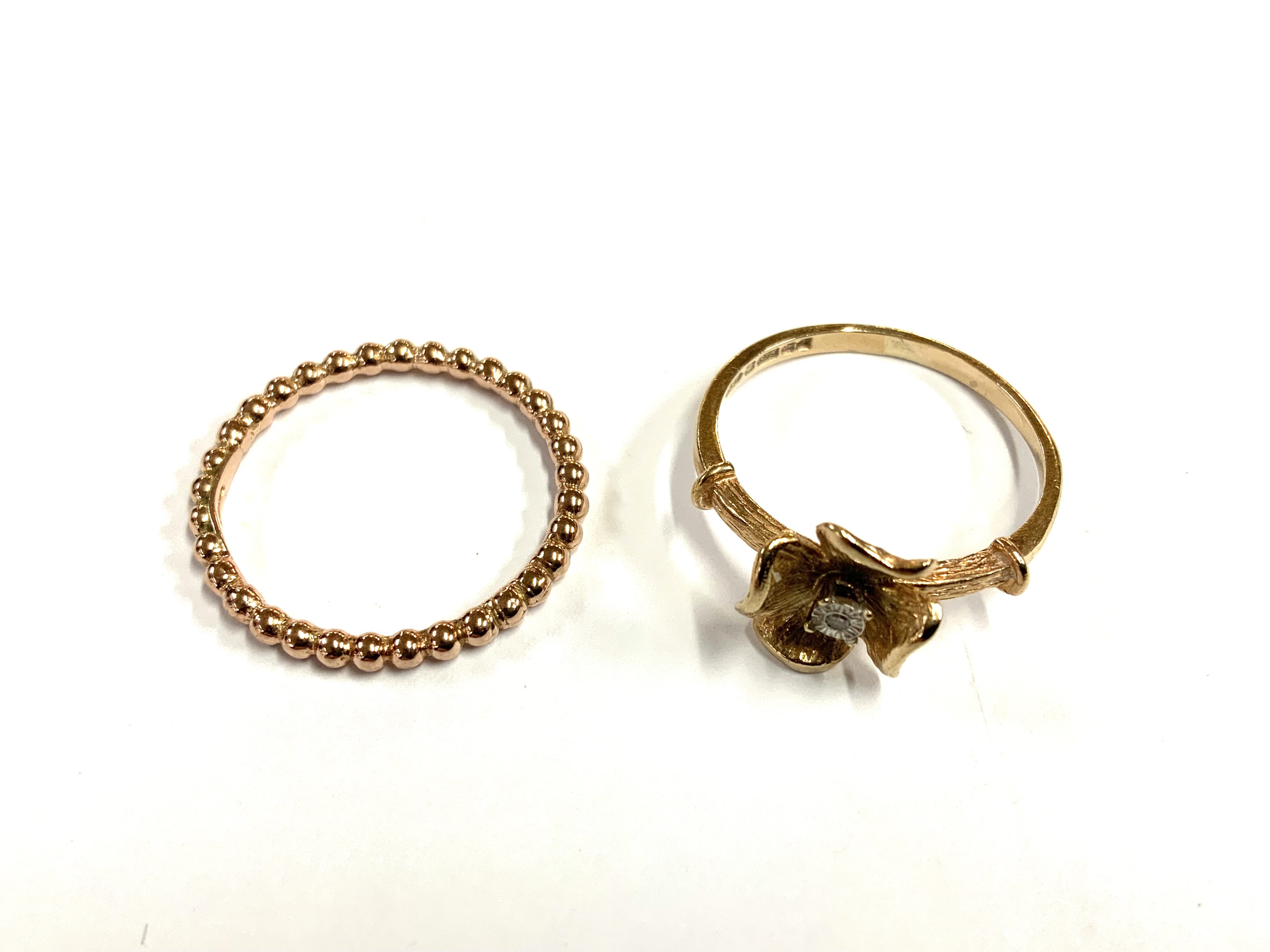 A 9ct gold band, Size P together with a 9ct gold flower ring, Size Q inset with a small chip diamond