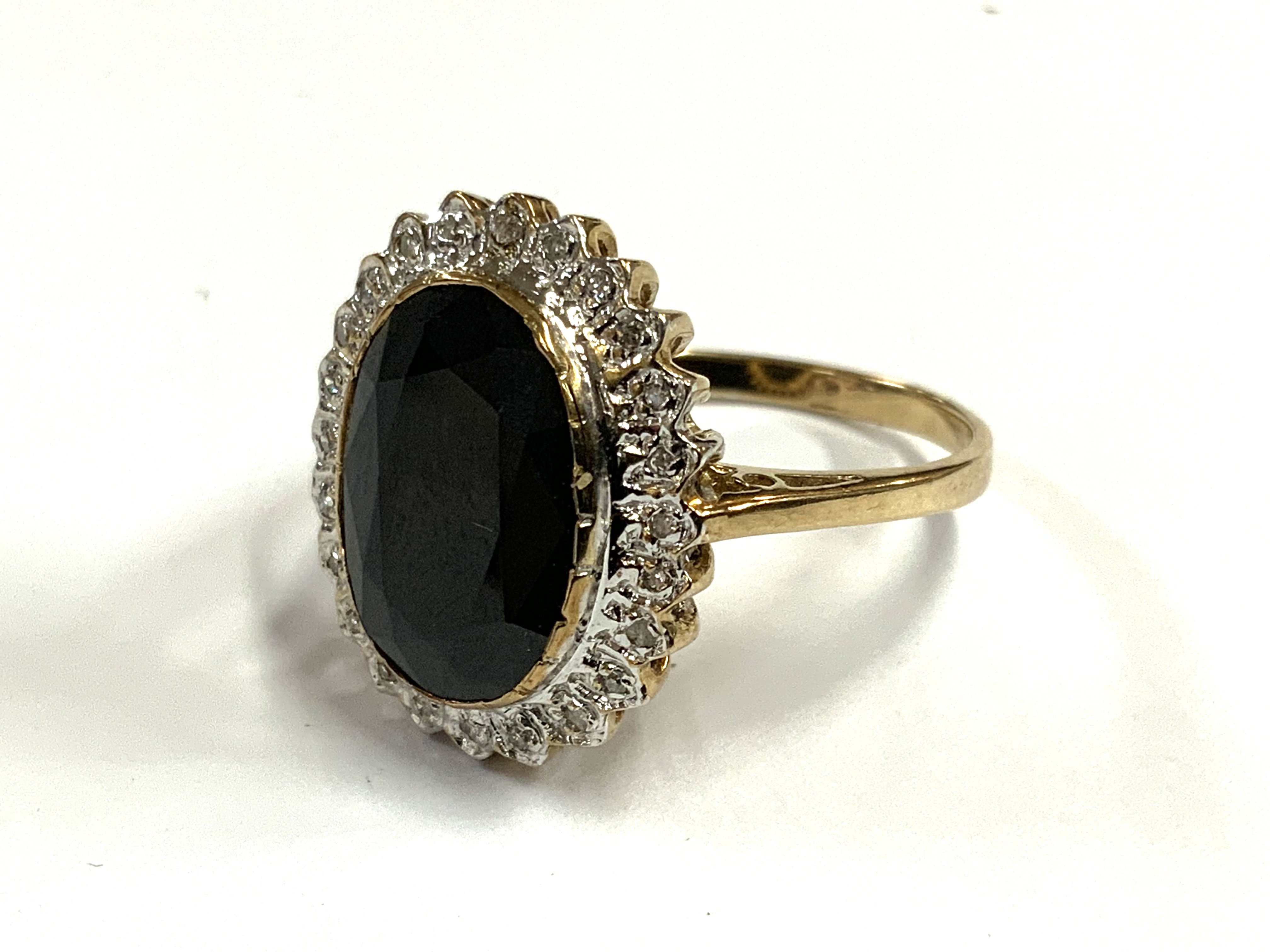 A 9ct gold ring set with a large blue central sapphire and surrounded by small cut diamonds. (A)