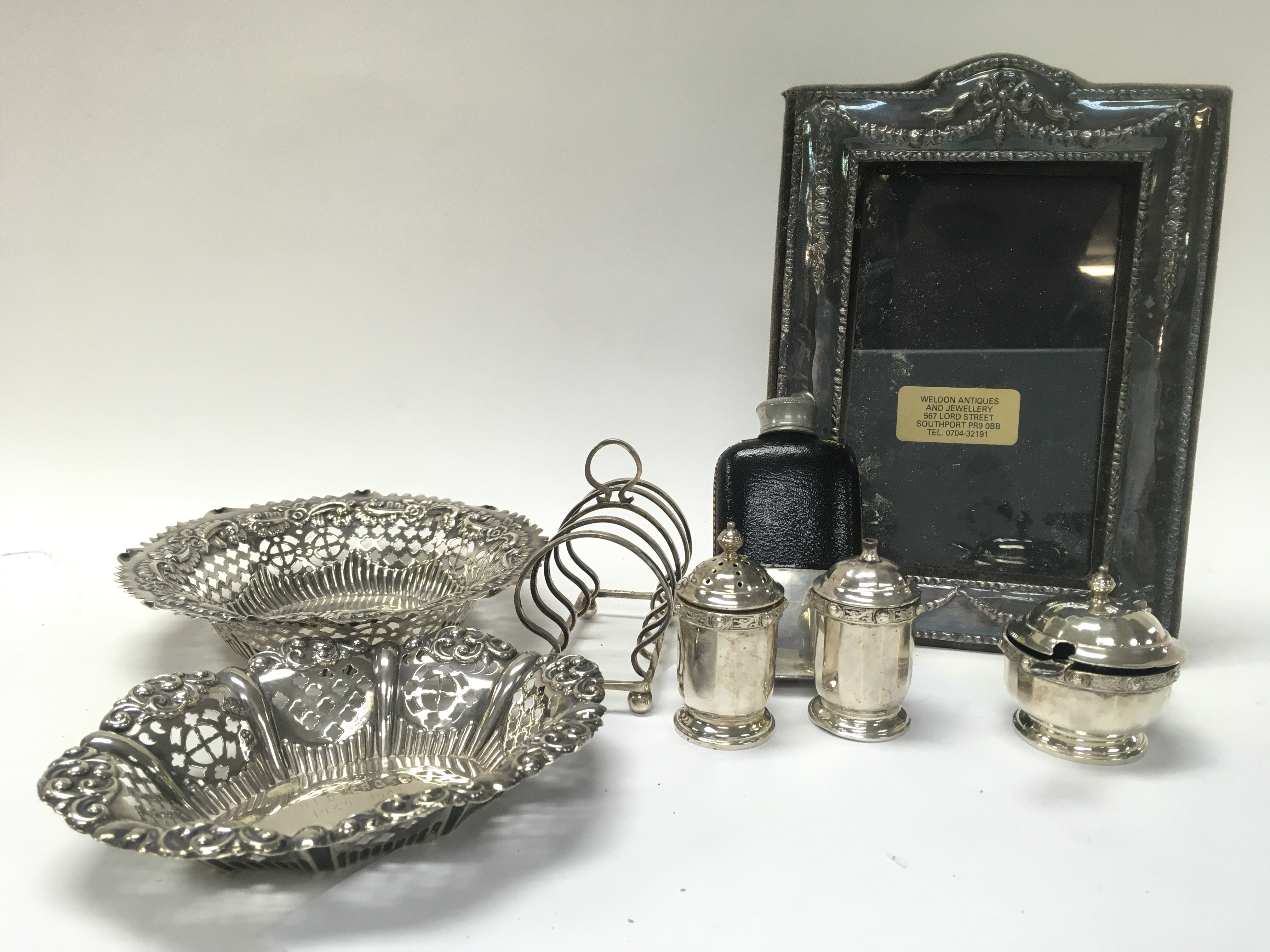 A Collection of silver hallmarked items including bonbon dishes, a photo frame, Scottish silver S/P shakers, rack, non silver flask. This lot cannot be posted