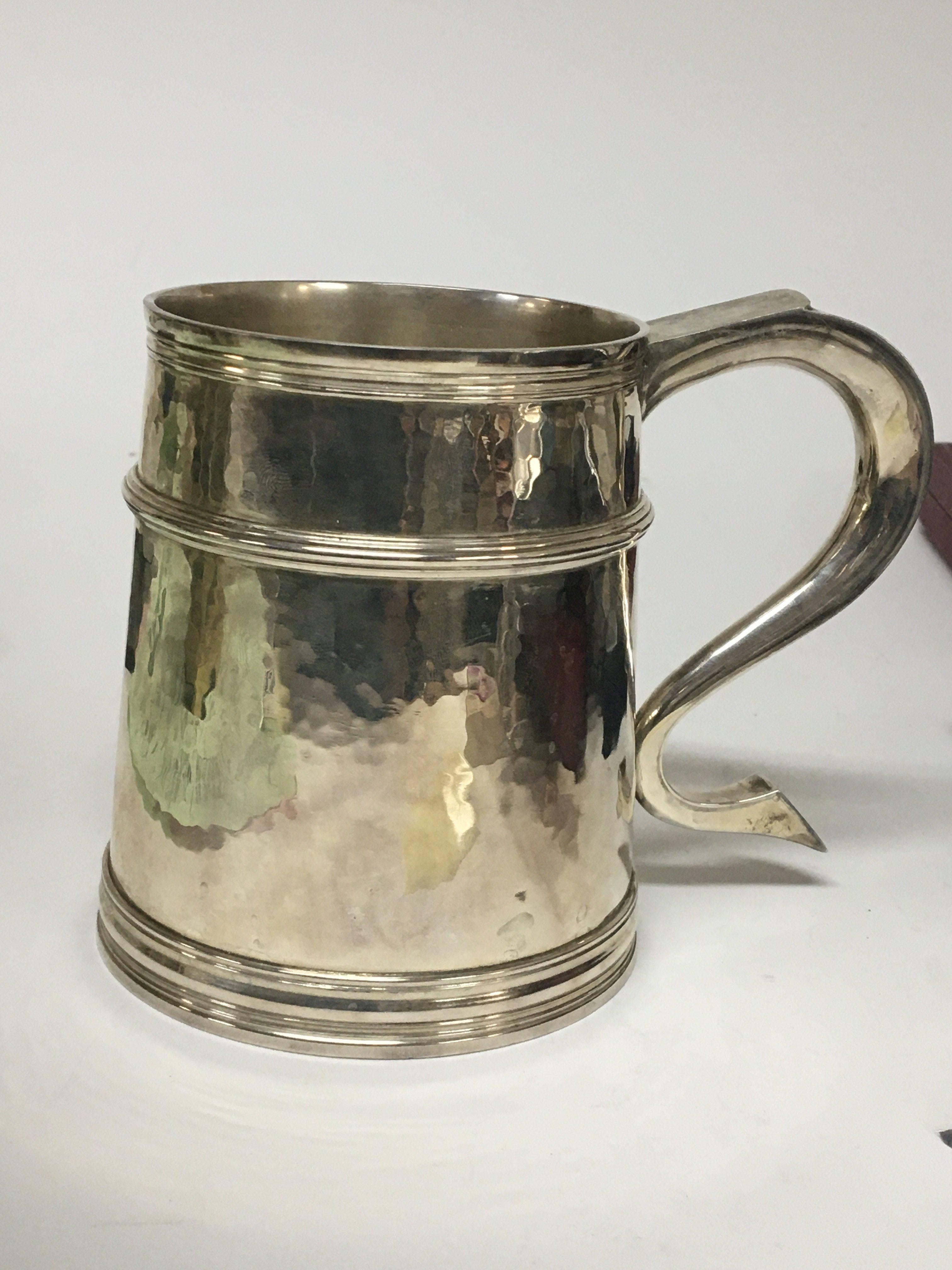 A Quality silver tankard of 18th century design with a shaped handle and hammered pattern sides with raised turning London hallmarks makers initials RC. Weight 580g no personal inscriptions and very good condition.