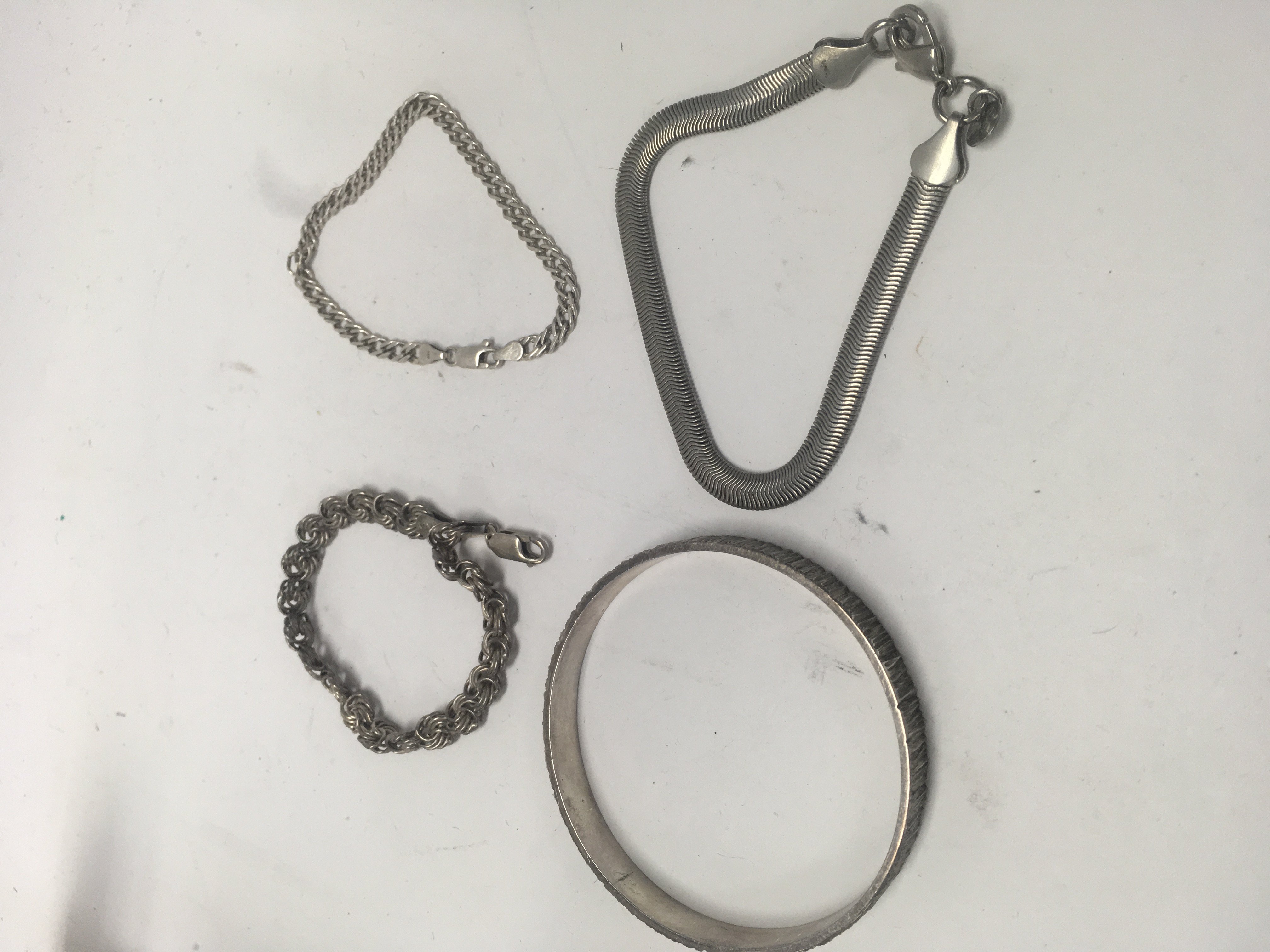 A silver bangle and three silver bracelets.