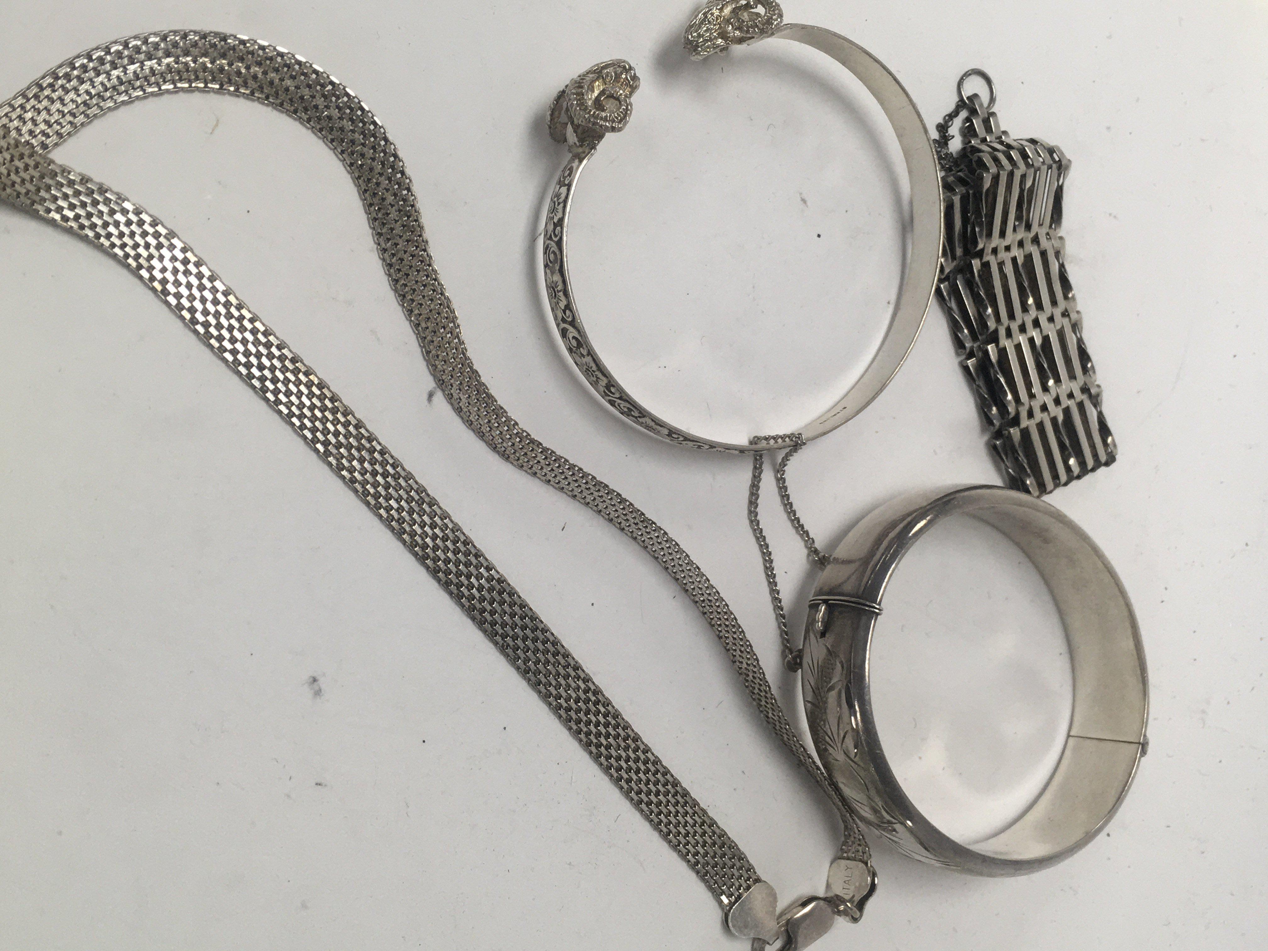 Two silver bangles a silver necklace and a silver gate bracelet.
