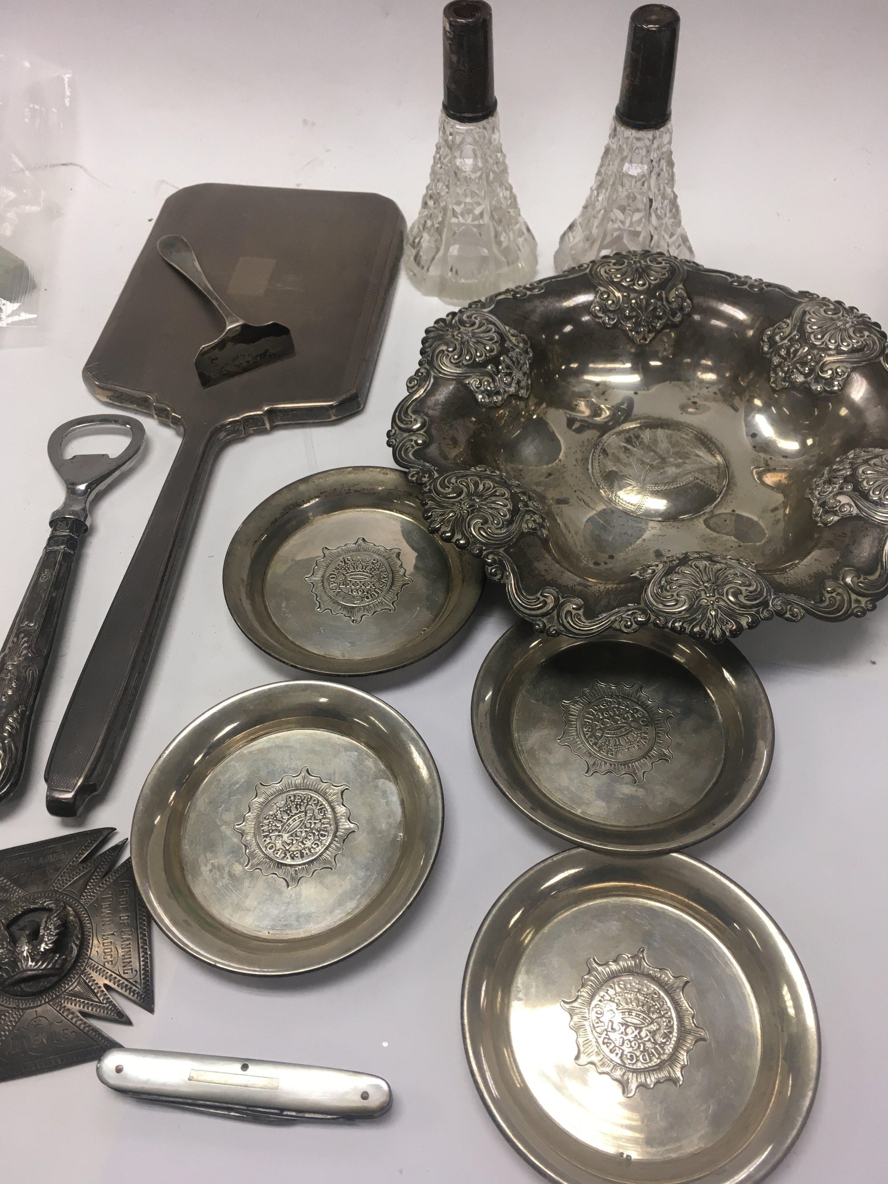 A Collection of silver including four dishes , perfume bottles ( no stoppers ) hand mirror bottle opener medallion and penknife.
