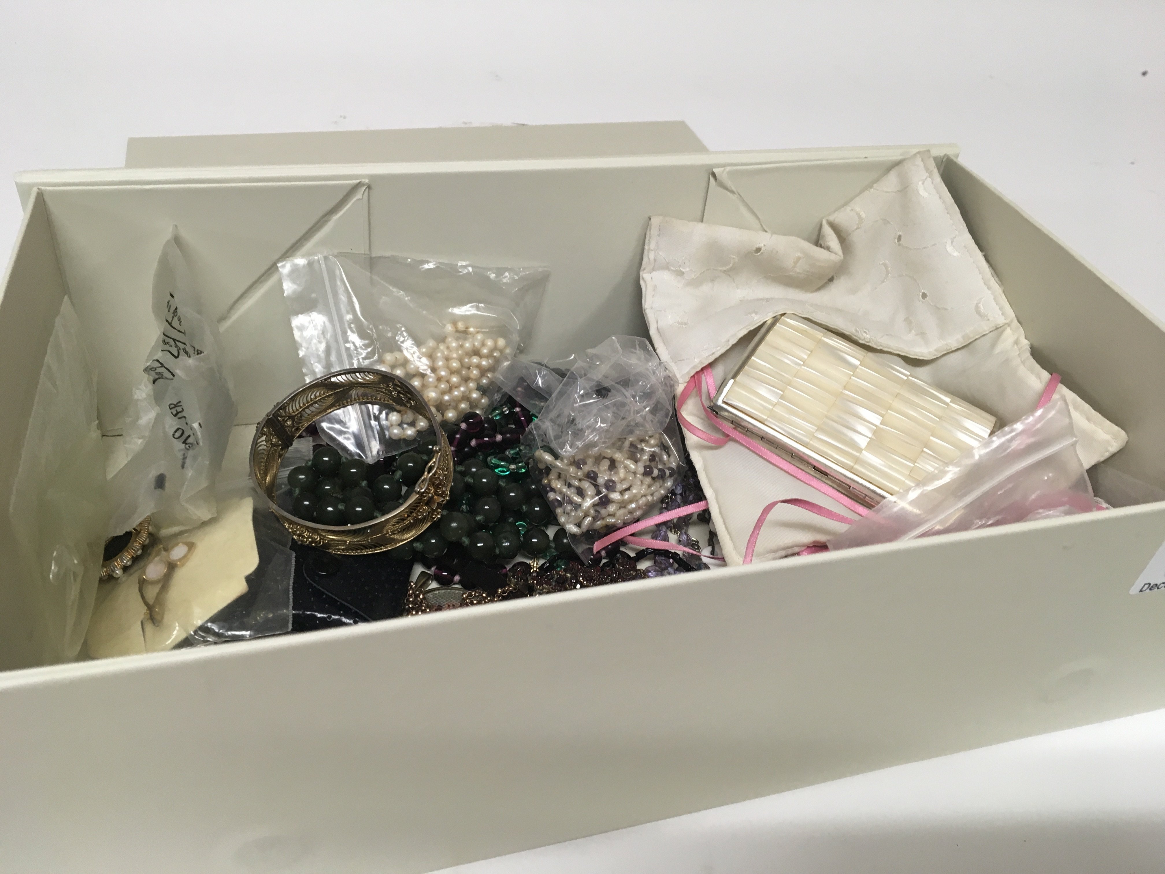 A box containing costume jewellery including a green jade necklace an antique garnet necklace pearl necklaces and other ornaments.