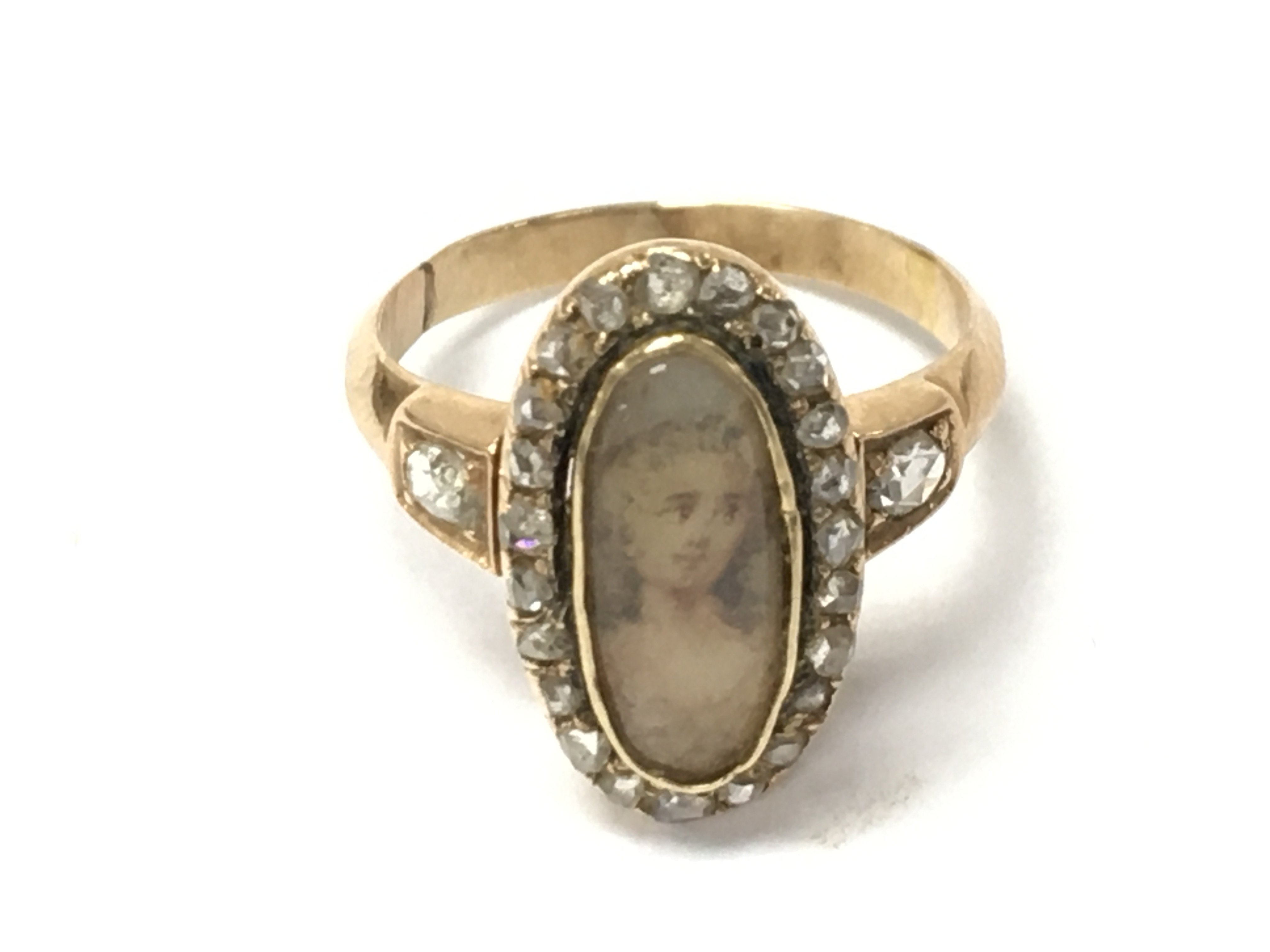 An antique gold ring set with an oval portrait with diamonds surround. 3.17g and size J Postage B