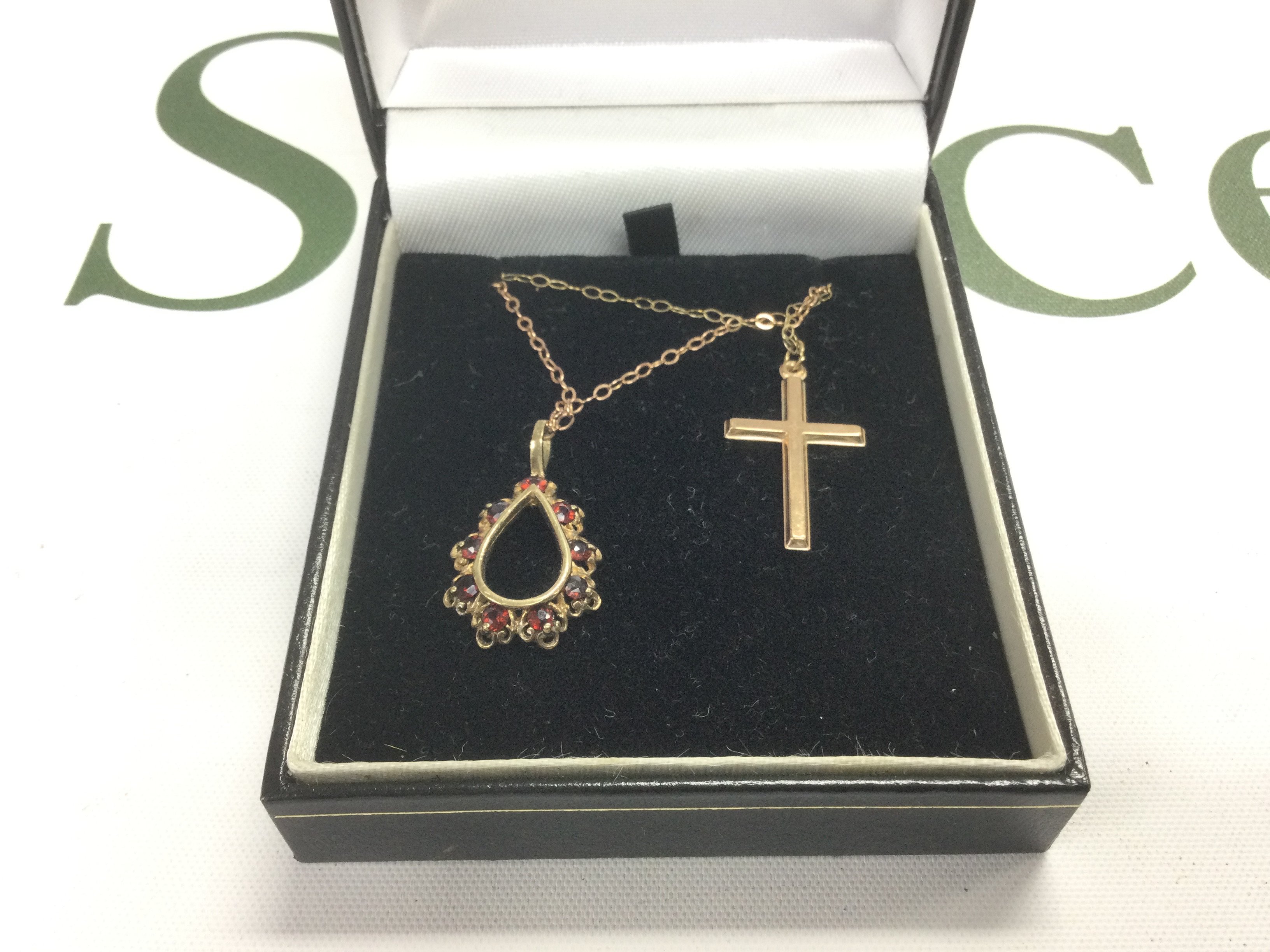 Two 9ct gold pendants on chains comprising a cross and one set with garnets. Shipping category A.
