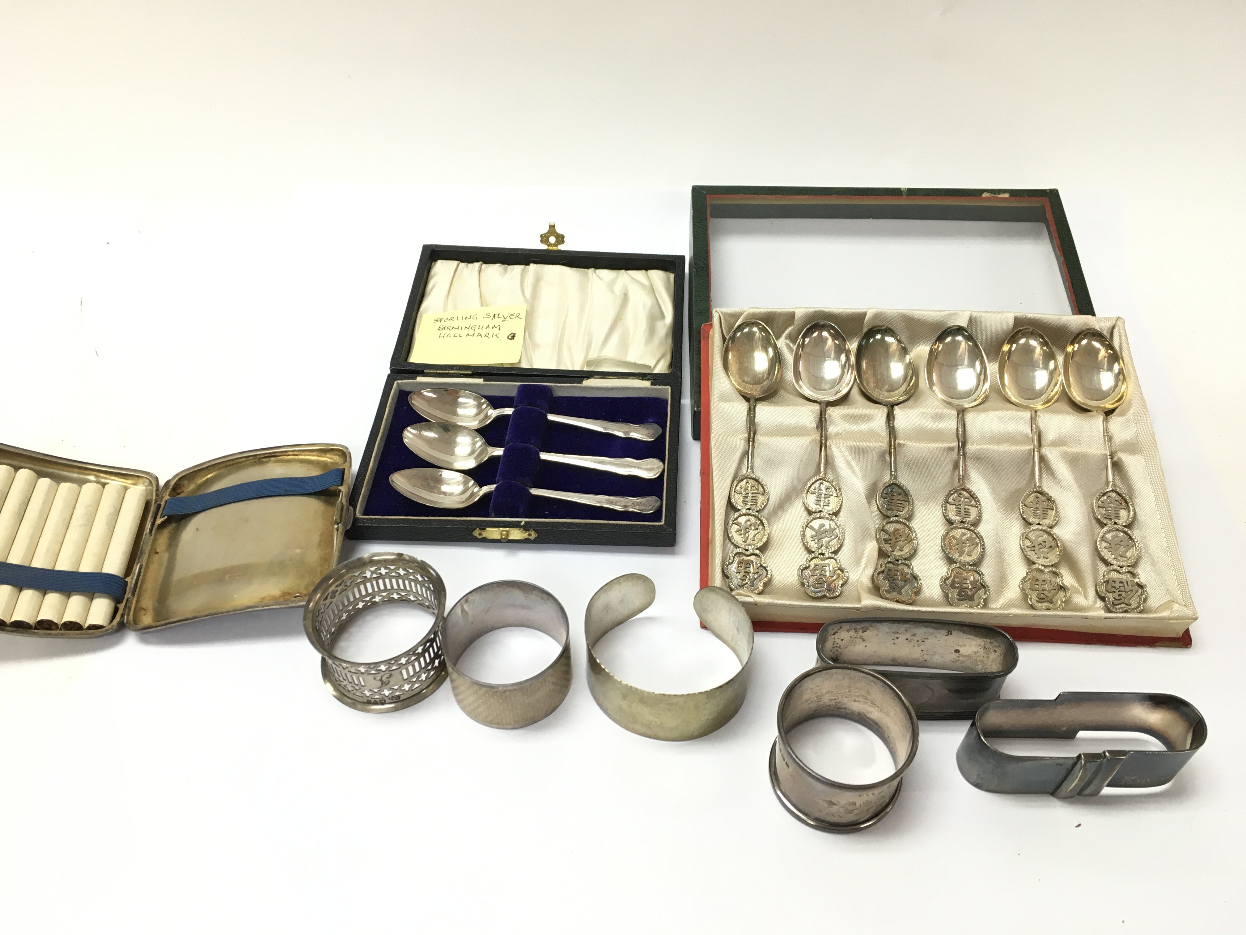 A silver cigarette case napkin rings silver Chinese spoons etc. Postage B
