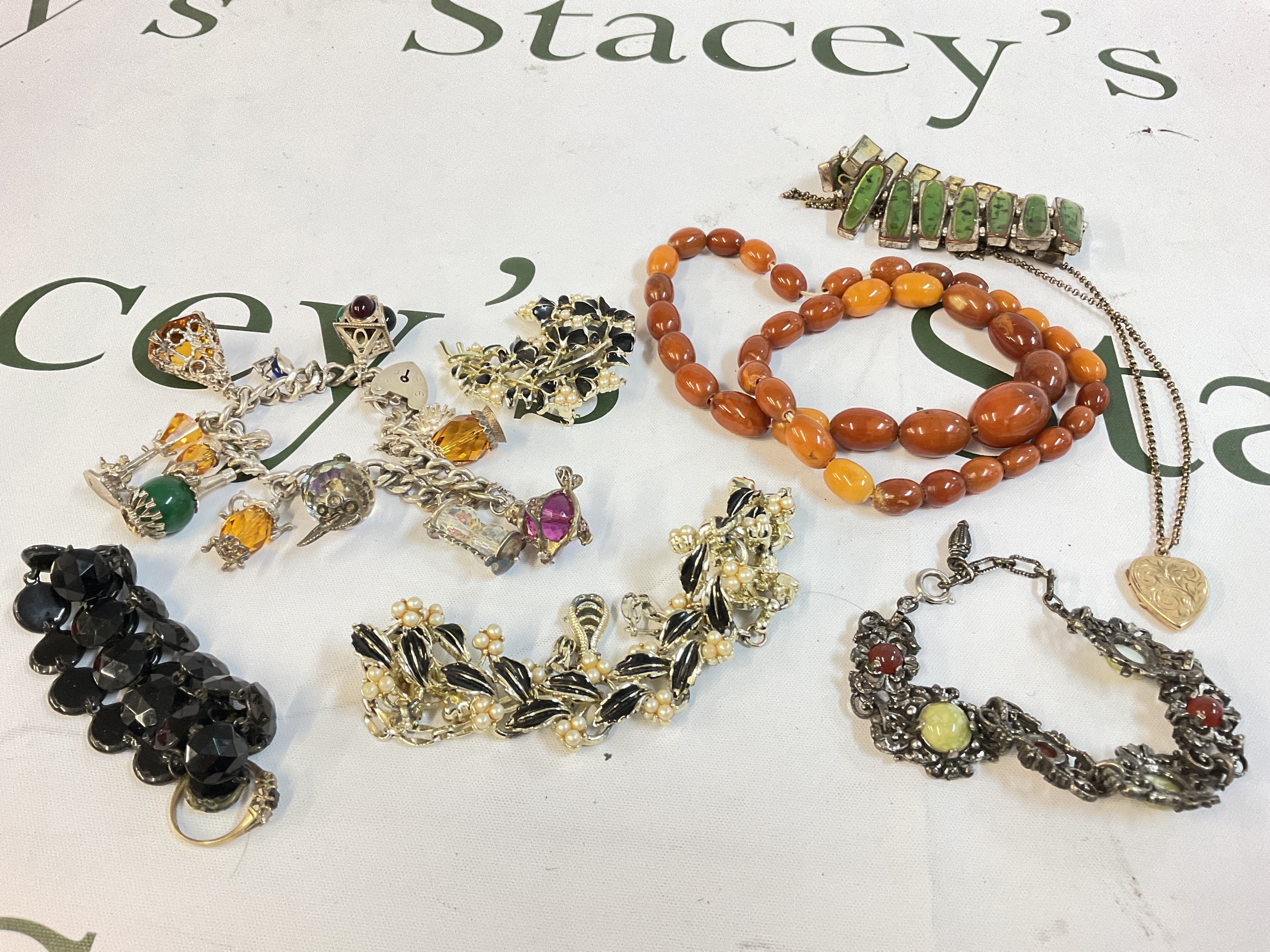 A collection of jewellery including a 9ct gold ring, a silver charm bracelet, a 9ct gold locket heart pendant and other jewellery. Postage category A