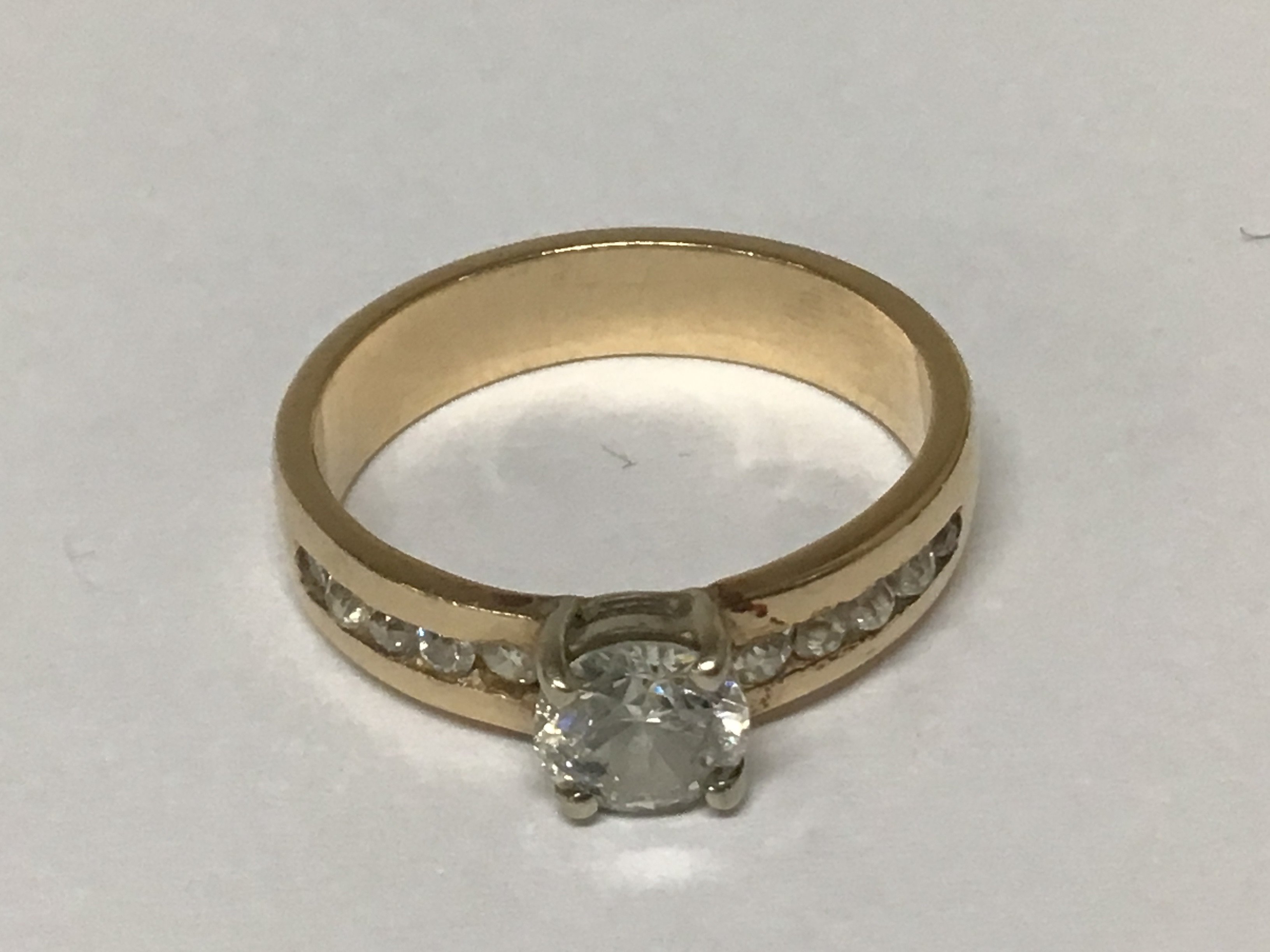 A gold ring set with a a half carat diamond the shank with a further row of small brilliant cut diamonds. Total weight 4.5g ring size P.