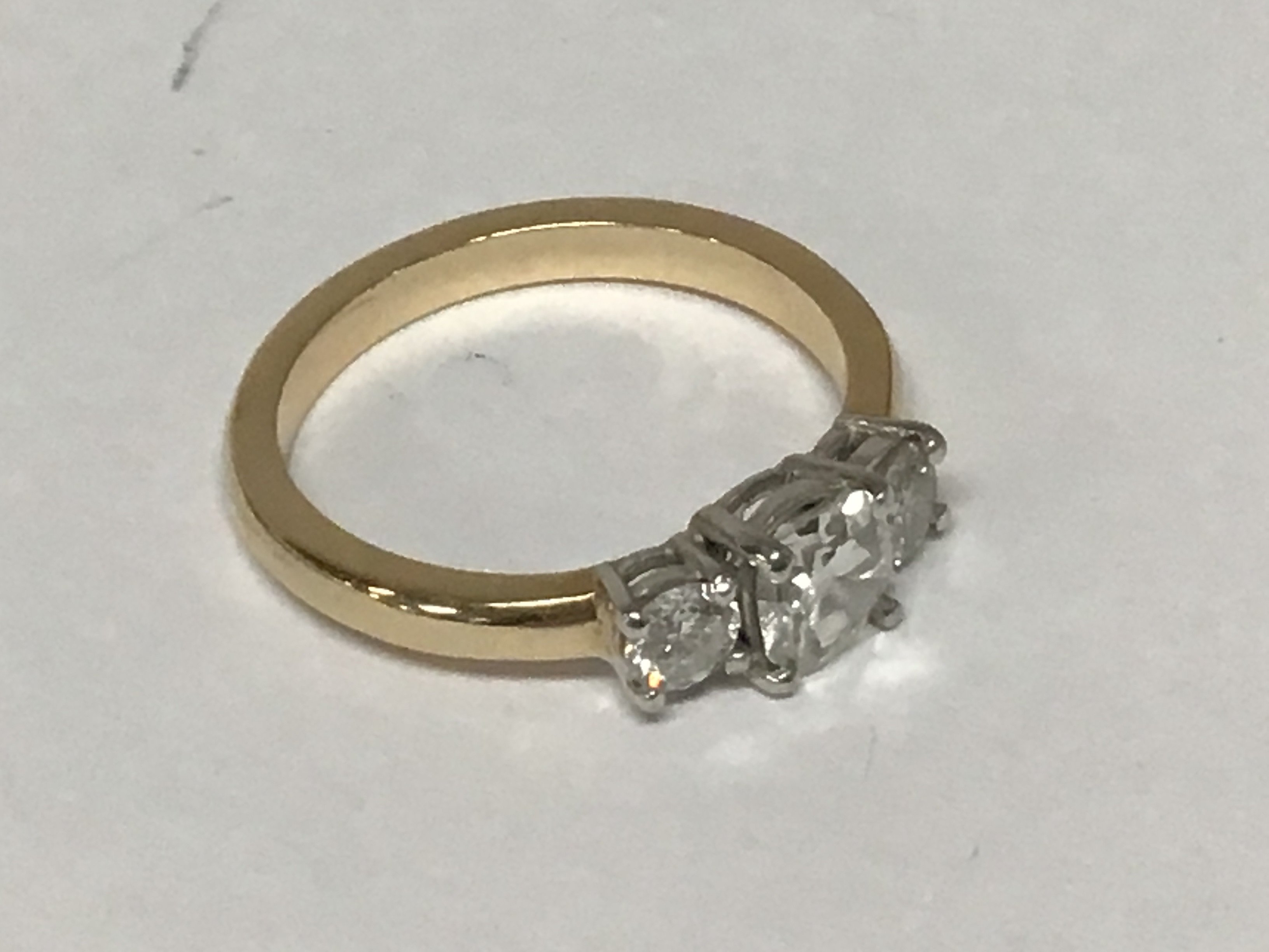 An unmarked gold ring set with three cushion cut diamonds the central stone approximately 0.70 of a carat flanked by two further diamonds approximately 0.20 of a carat ring size P. Weight 4g.