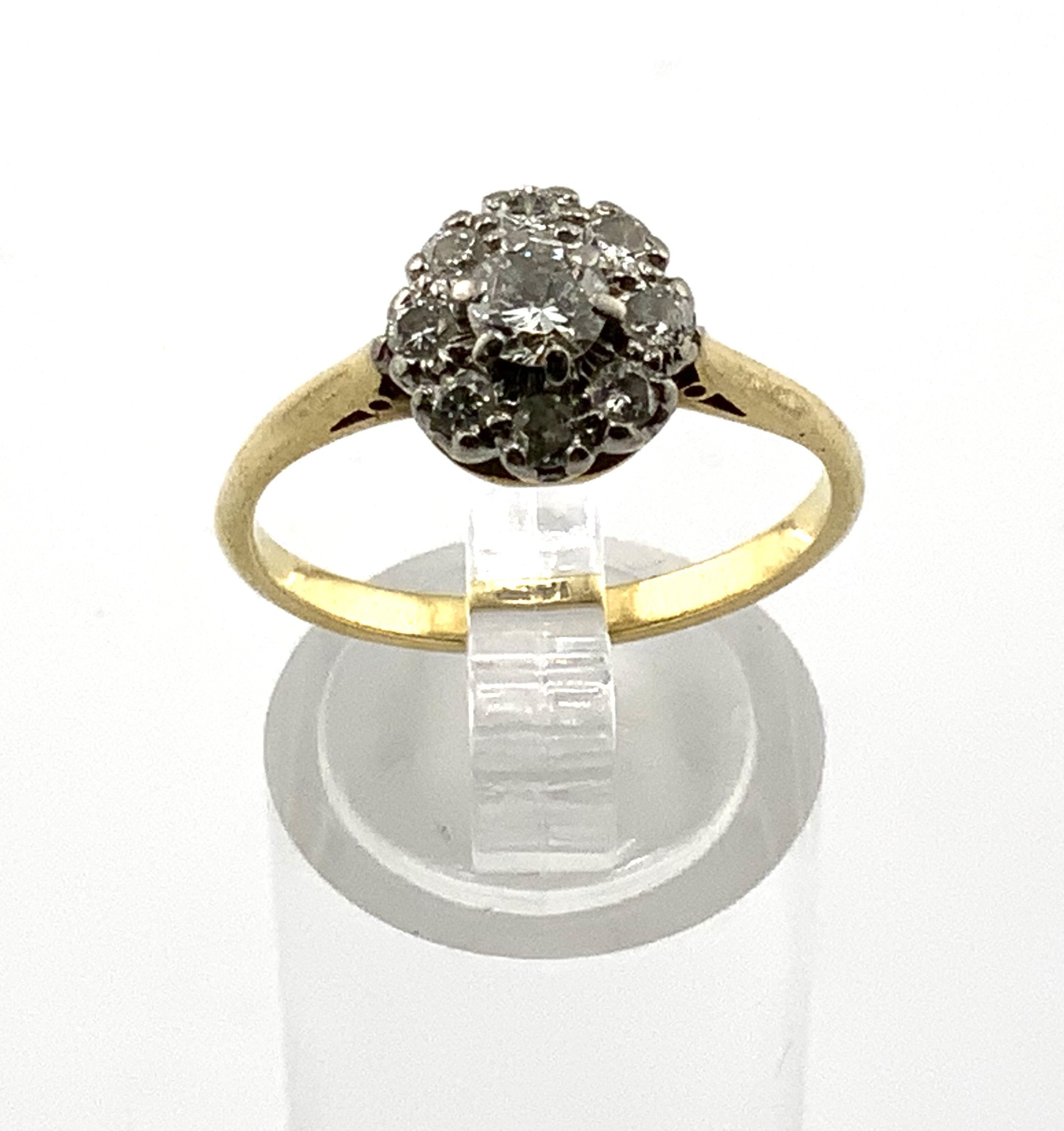 An 18ct gold diamond cluster ring set with a central 0.25ct centre stone. (A)