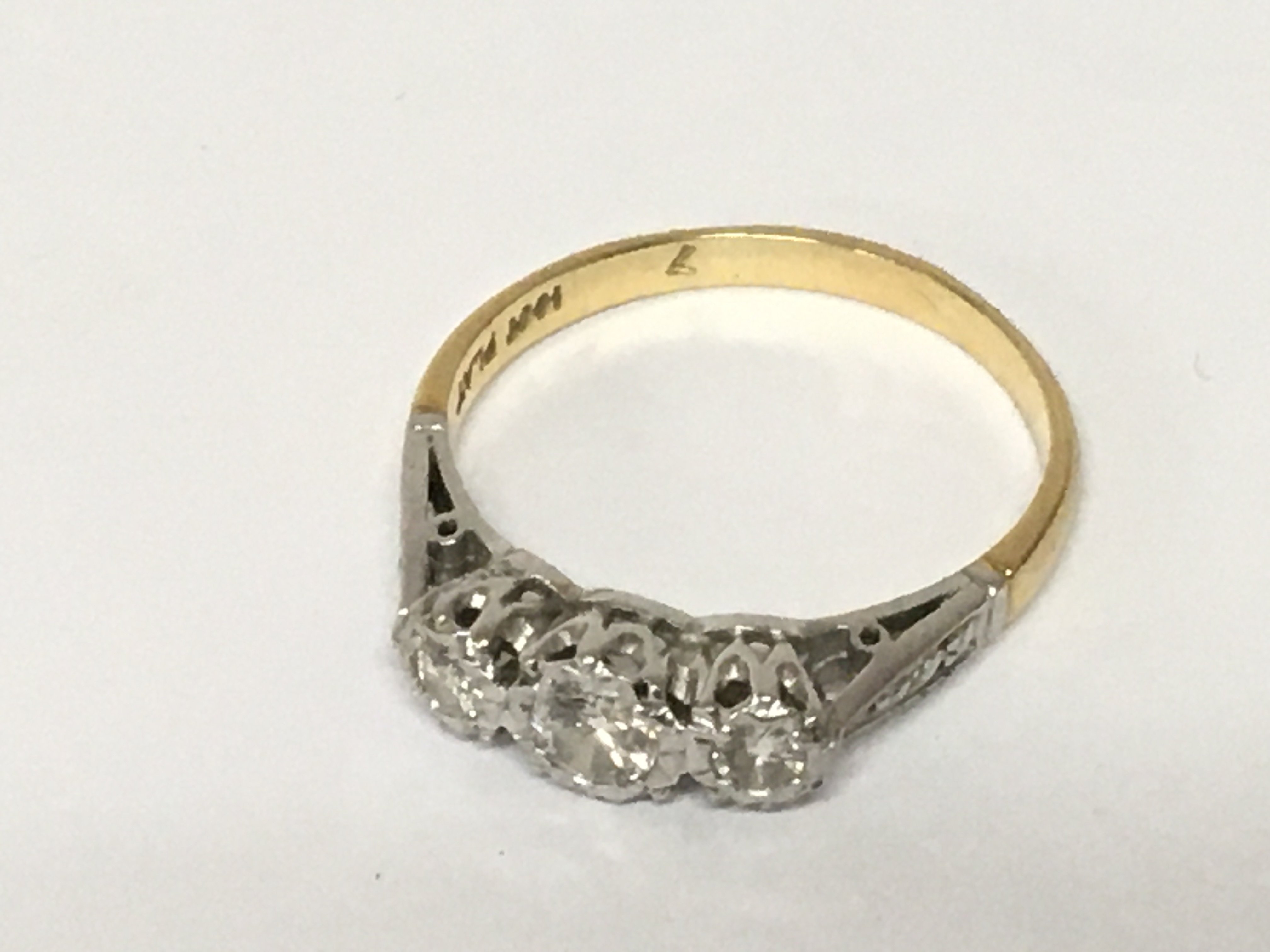 An 18carat gold and platinum ring set with a row of three diamonds. Ring size R weight 2.8g