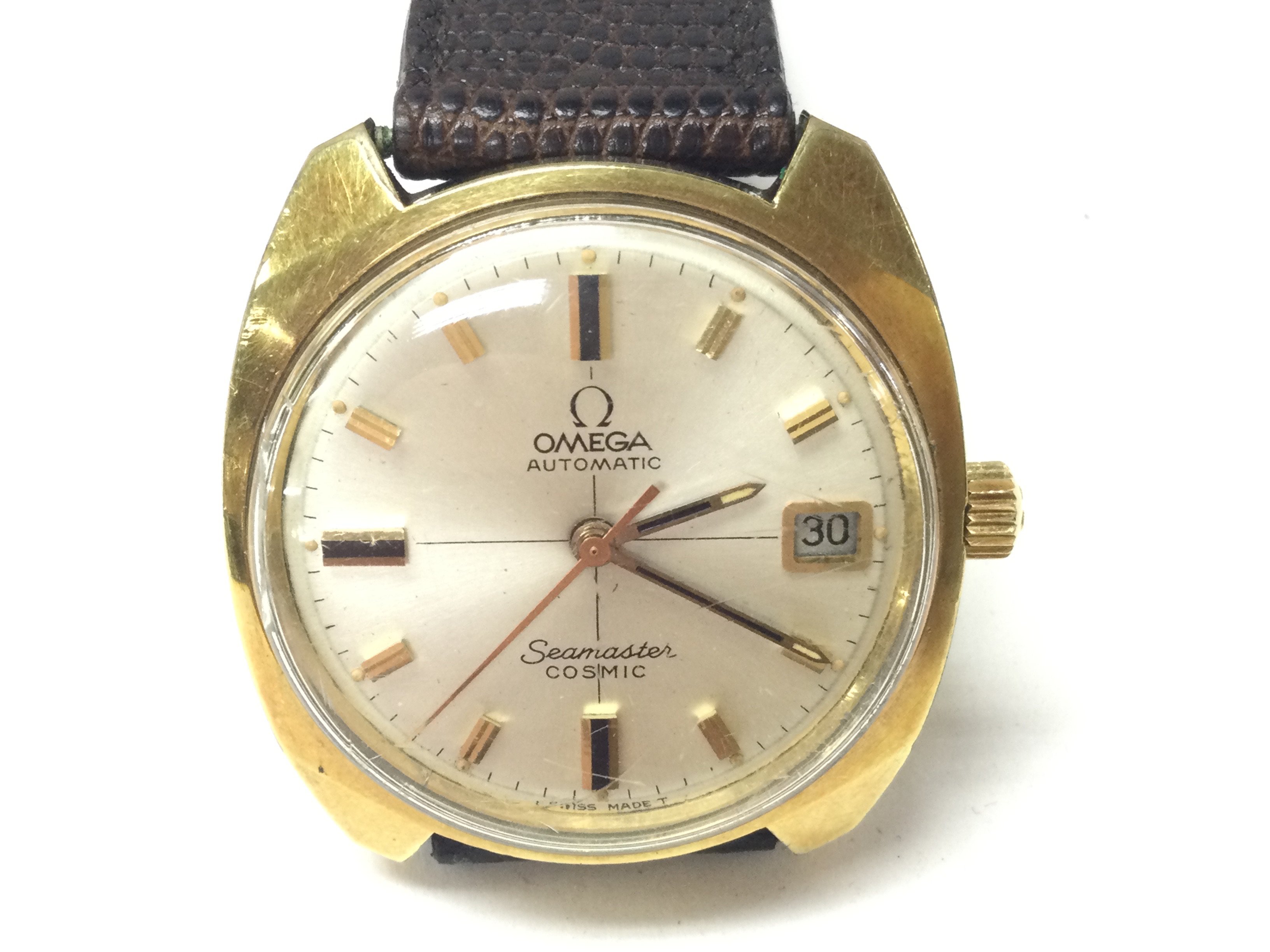 An Omega seamaster cosmic automatic date wrist watch. Gold plated case with baton markers and champagne dial. Brown leather strap with omega buckle and box. Seen running. Postage B