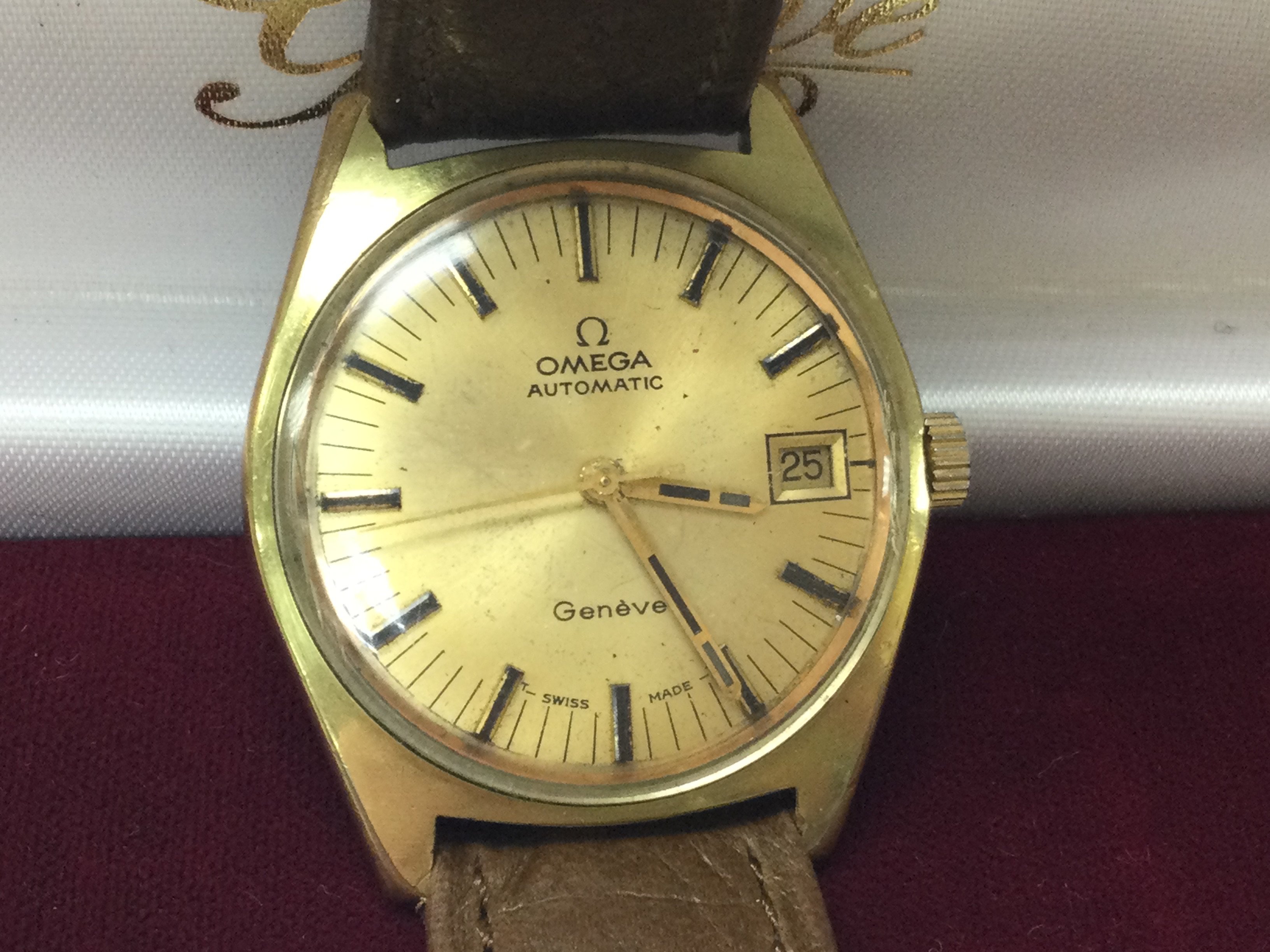 Am Omega Geneve automatic gold plated watch with tan strap and omega buckle. Circa 1971. Comes with box and seen running. Case approx 36mm. 565 cal. Postage B