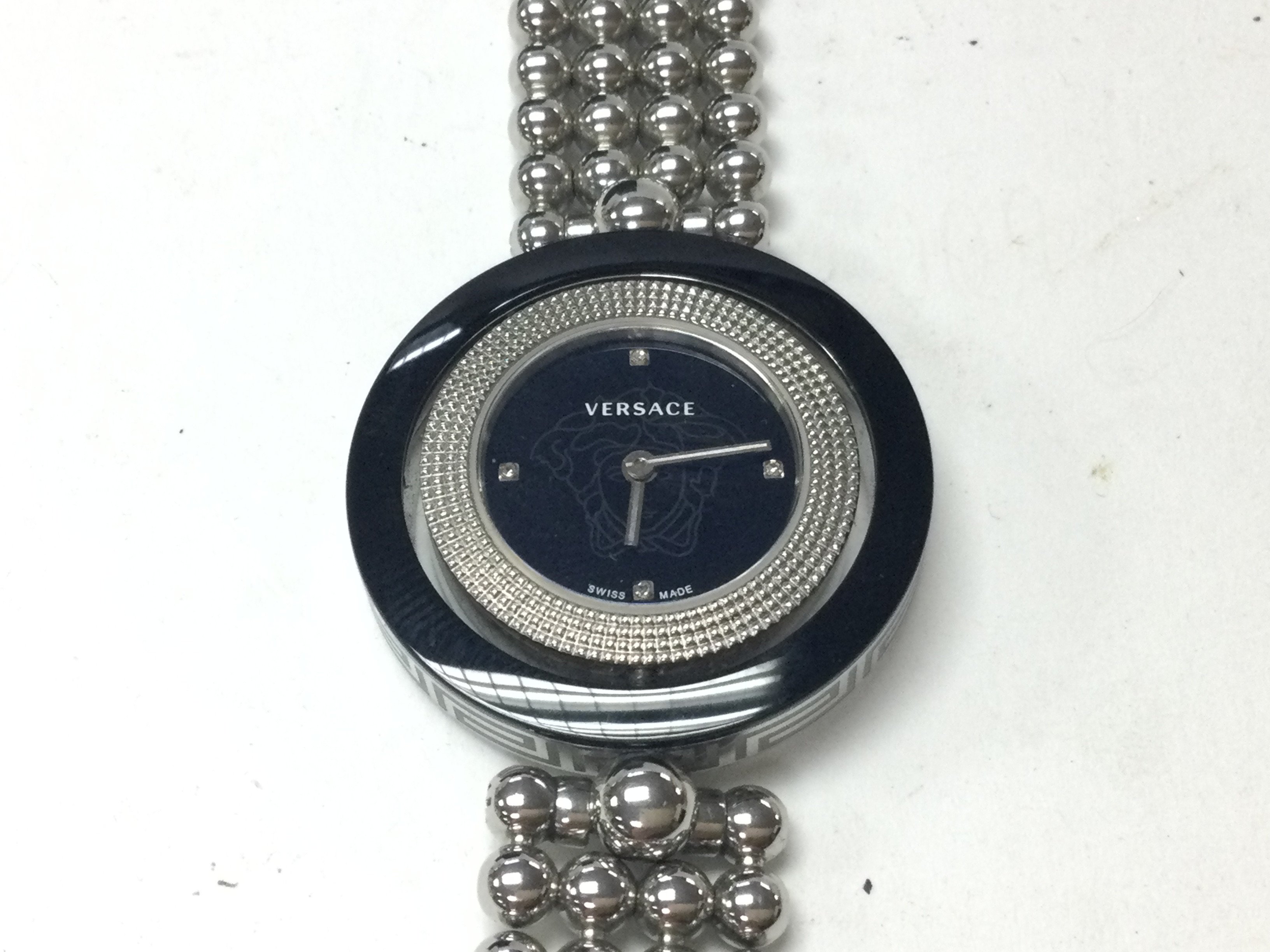 A Versace ladies watch with spinning bezel and round face with black dial. Comes with box. Postage B
