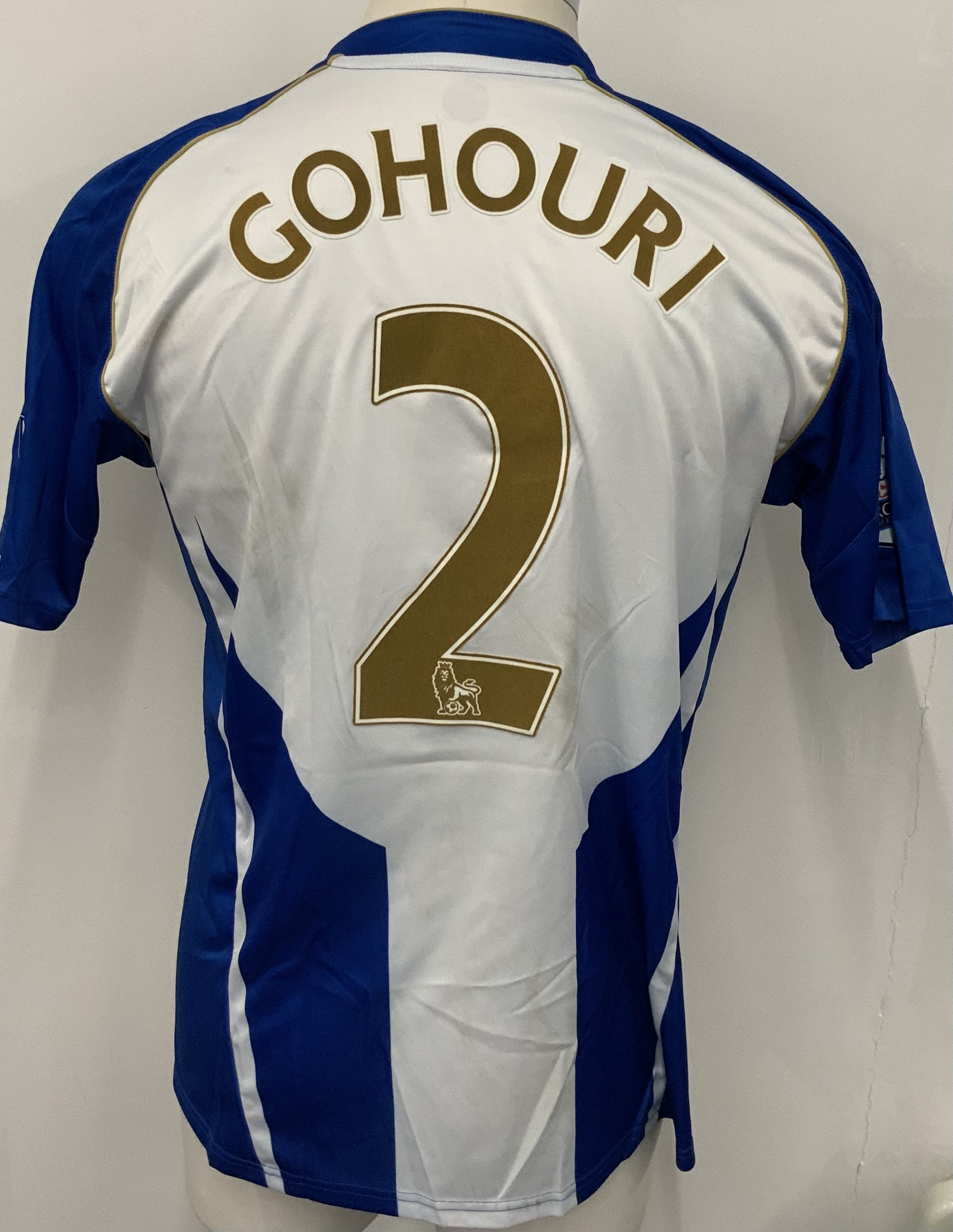 Wigan Athletic 2009 - 2010 Match Worn Football Shirt: Blue and white striped Vandanel 188 Bet short sleeve shirt with Premier League badging to sleeves. Number 2 Gohouri to rear. Worn v Portsmouth. Mud marks.