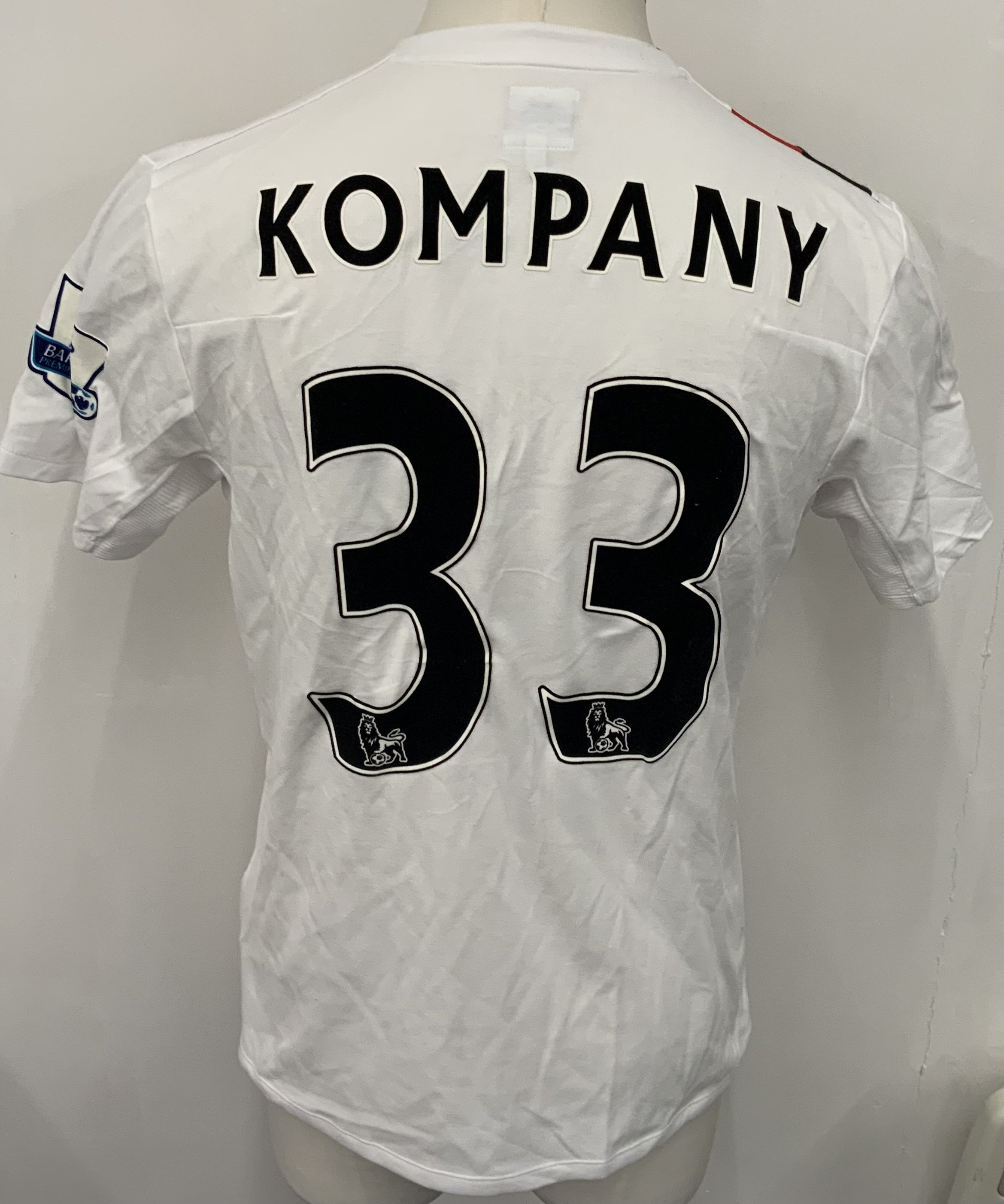 Manchester City 2009 - 2010 Kompany 3rd Kit Match Worn Football Shirt: White with red and black slash short sleeve Umbro shirt from 1st season of Etihad Sponsorship. Premier League badging to sleeve and Kompany 33 to rear. 