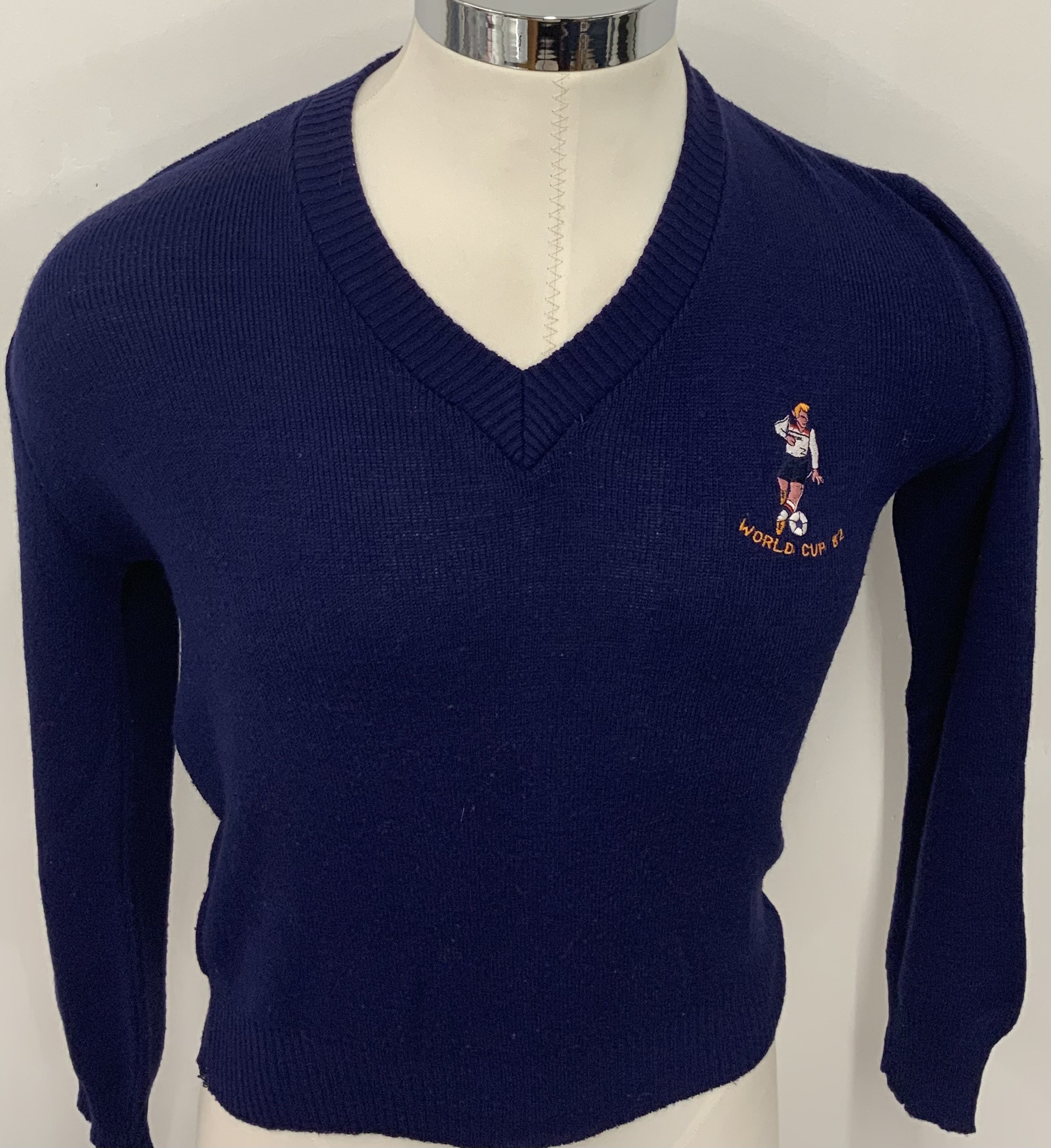 England World Cup 1982 Football Jumper: V neck in size 38 has England player in 1982 kit above wording World Cup 82. Good but couple of stitches required near neck as shown. 