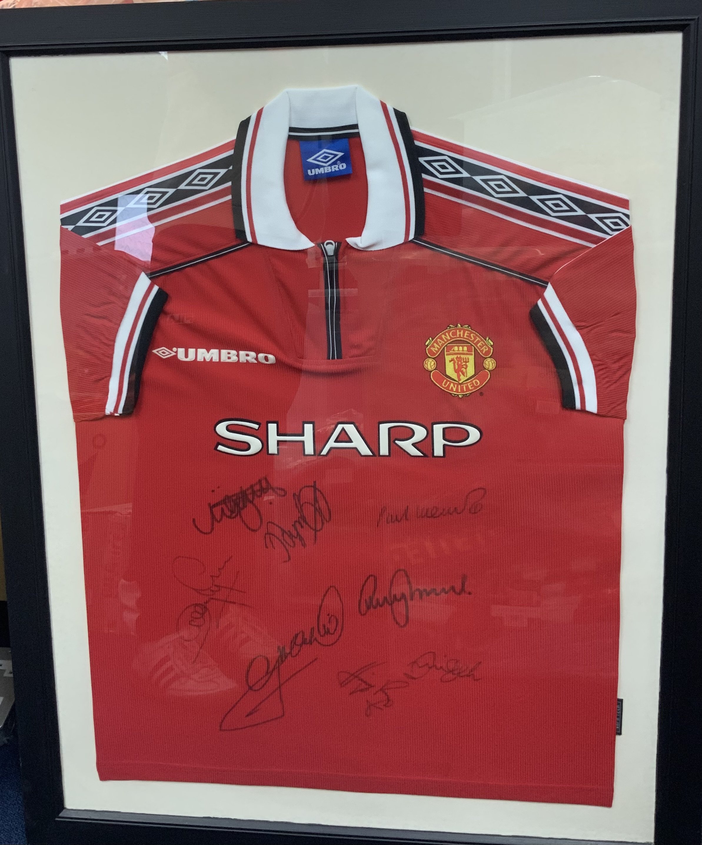 Manchester United 1998 - 1999 Treble Winners Signed Framed Shirt: Signed by seven players including Beckham. Frame measures approximately 38 inches by 31 inches. Original home shirt from the day. No COA. Not for posting. 