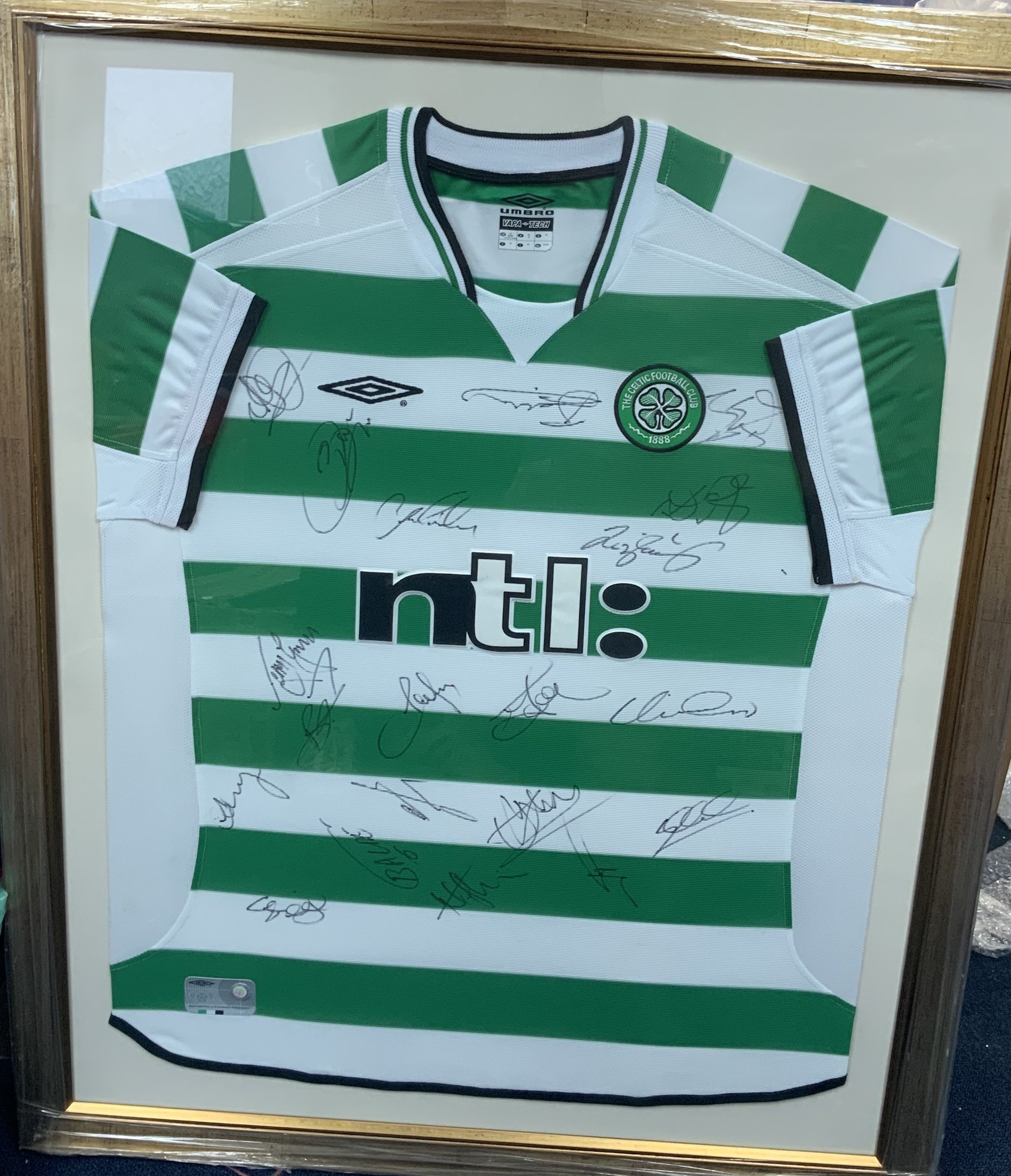 Celtic 2002 - 2003 Framed Multi Signed Football Shirt: Green and white hooped XL shirt. Squad signed with COA. Also comes with signed pennant. Frame measures approximately 38 inches by 31 inches. Not for posting. (2)